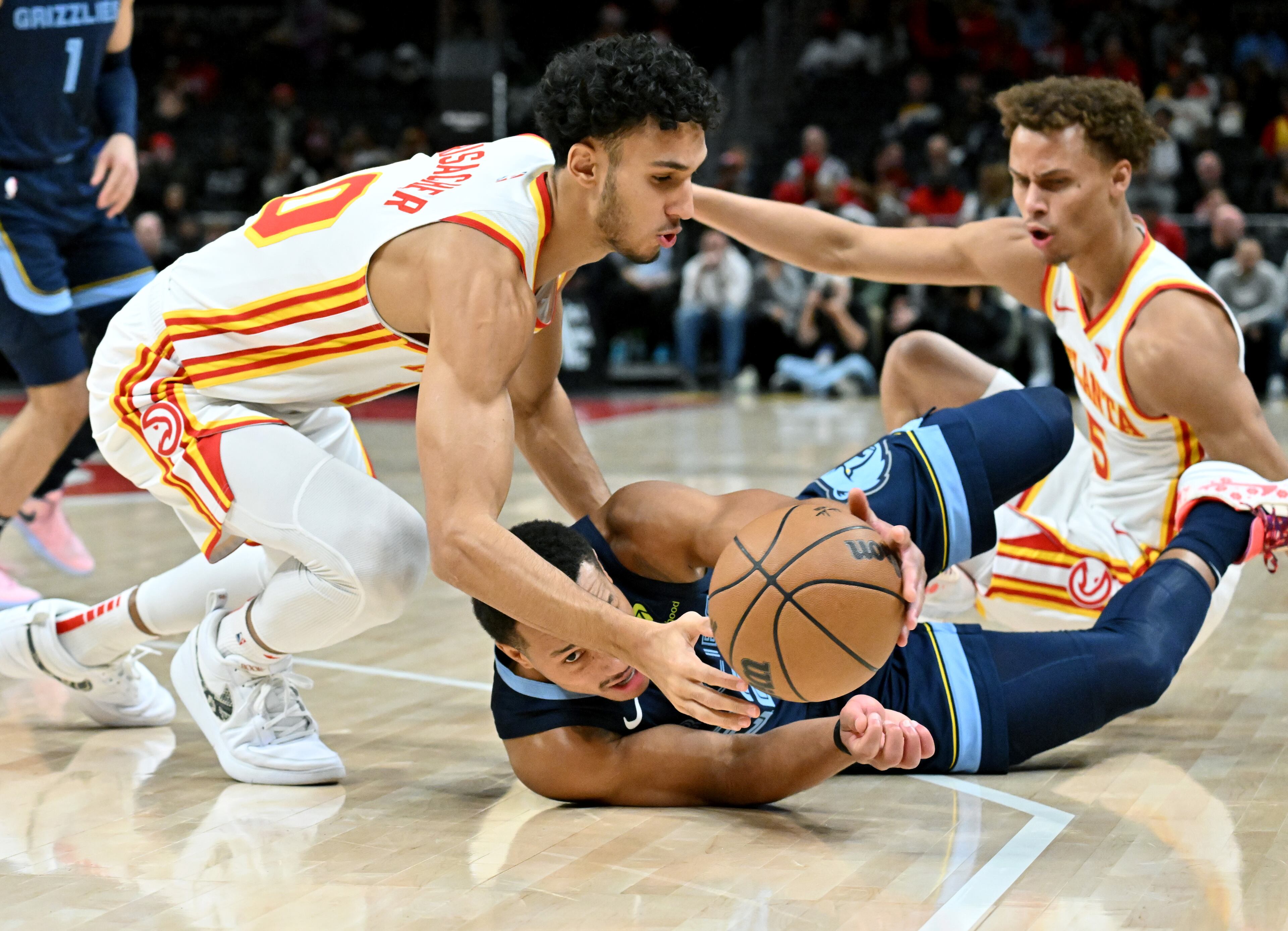 Hawks forward Zaccharie Risacher (10) fights for a loose ball against Grizzlies guard Desmond Bane (22) during the first half in an NBA basketball game at State Farm Arena, Saturday, December 21, 2024, in Atlanta. (Hyosub Shin / AJC)