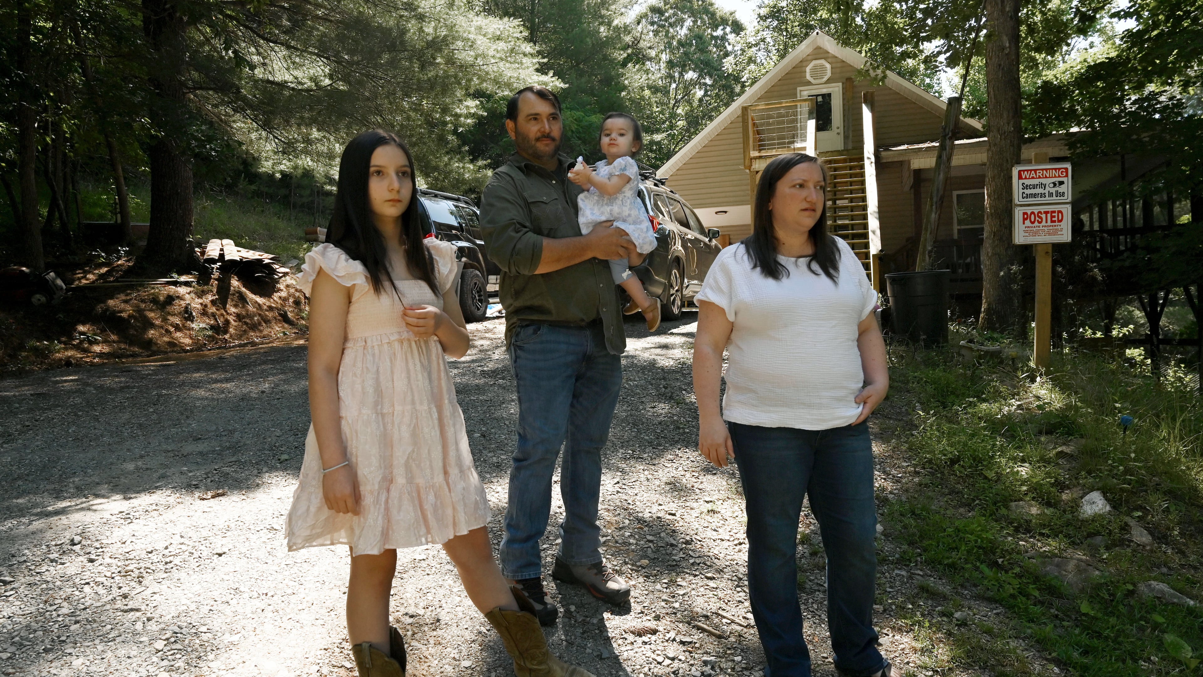 Kristy Guarnieri (right) and husband Courtney Guarnieri stand with their daughters, Stella, 12 (left) and Eliza, 1, on their property in Morganton in North Georgia on Thursday, June 4, 2026. They say their lives have been upturned by animals getting loose from the nearby Hooves and Feathers Petting Farm. (Hyosub Shin/AJC)