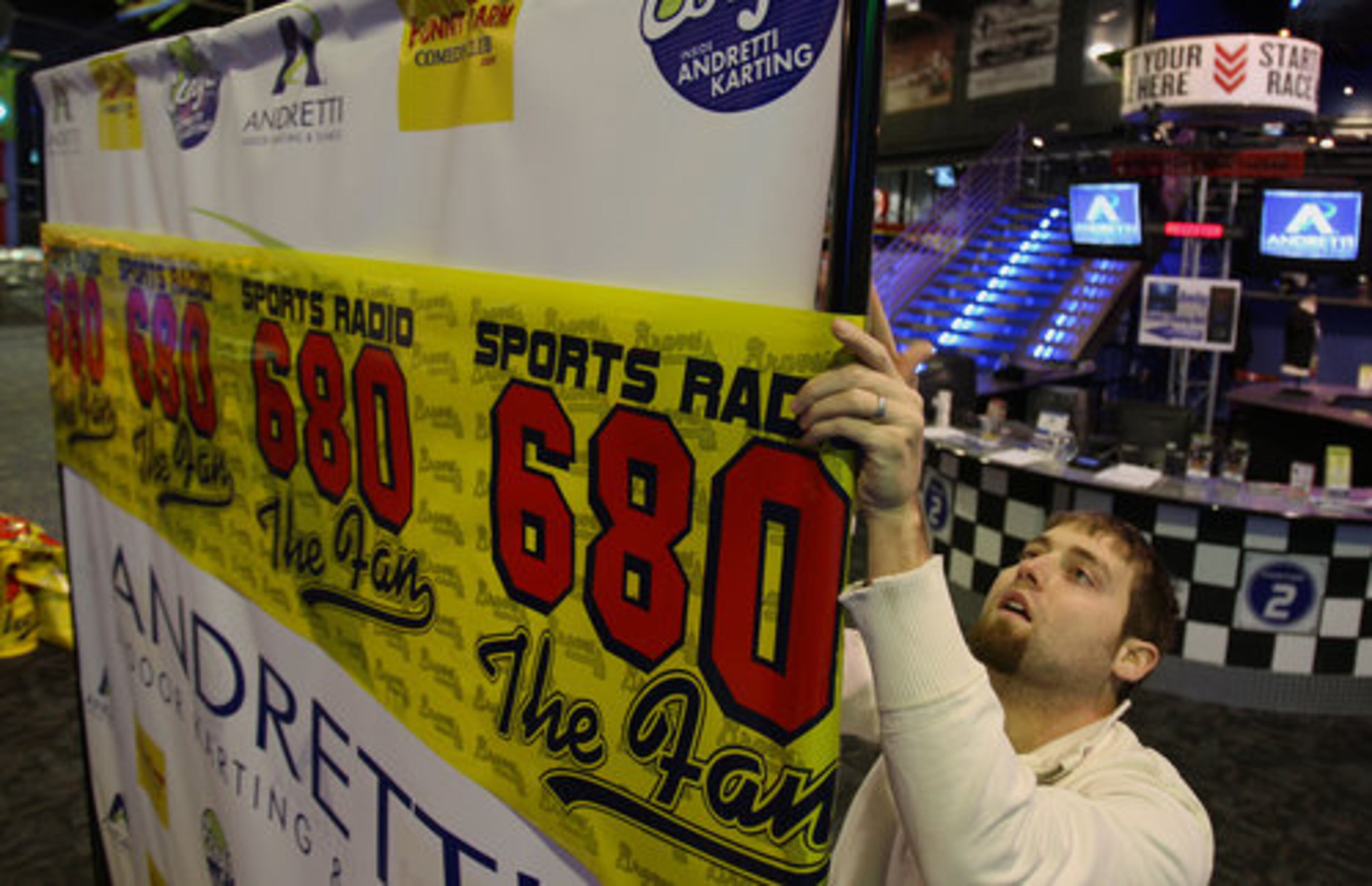 Austin Gooch of Sports Radio 680 hangs the banner at the Andretti Indoor Karting & Games where the 680 The Fan Signing Day Spectacular event will be held Wednesday, February 3, 2010.