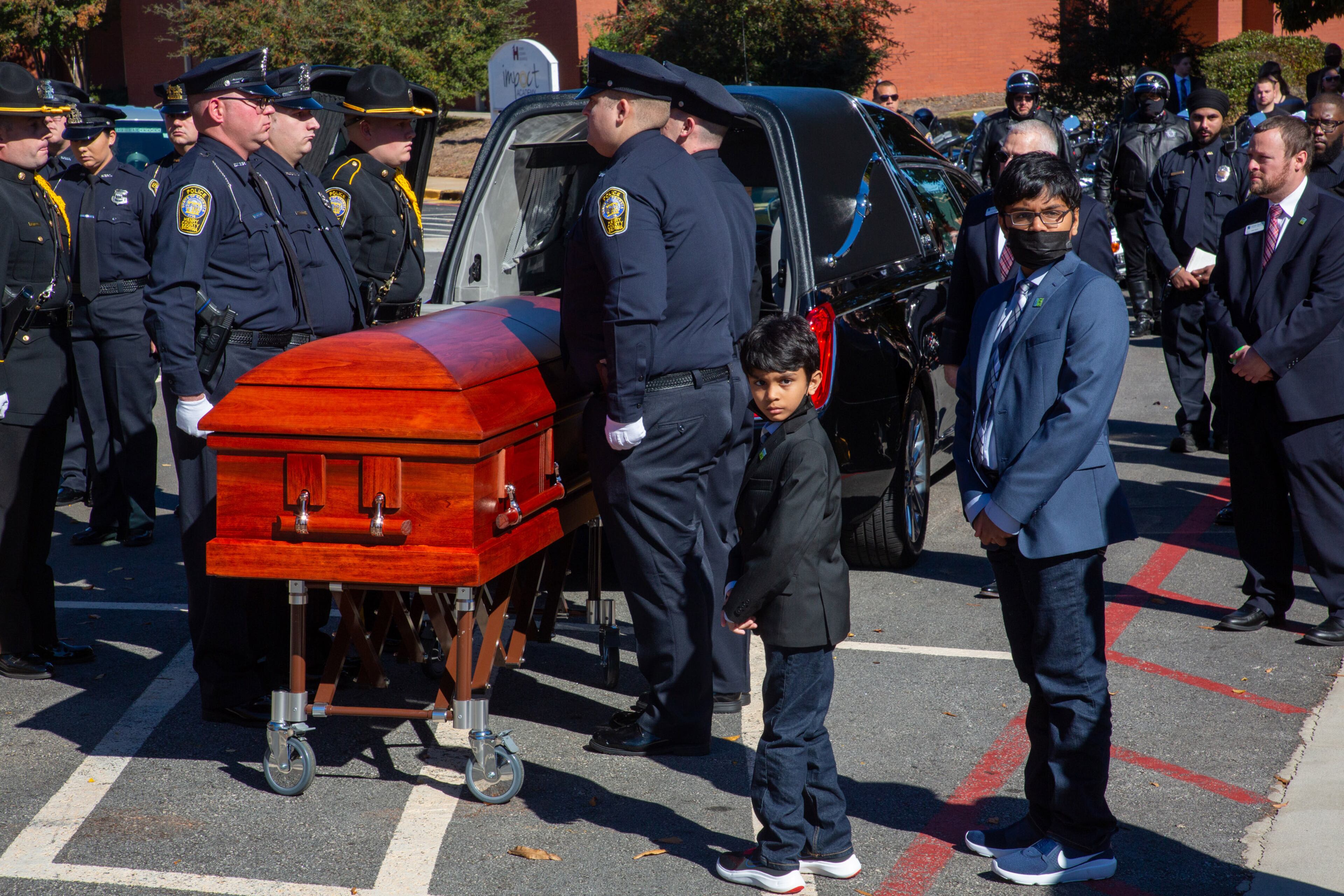 The two sons of slain Henry County police Officer Paramhans Desai, Om, 11, and Namah, 8, stand next to the coffin after the funeral service at the Henry County Performing Arts Center. (Photo: Steve Schaefer for The Atlanta Journal-Constitution)
