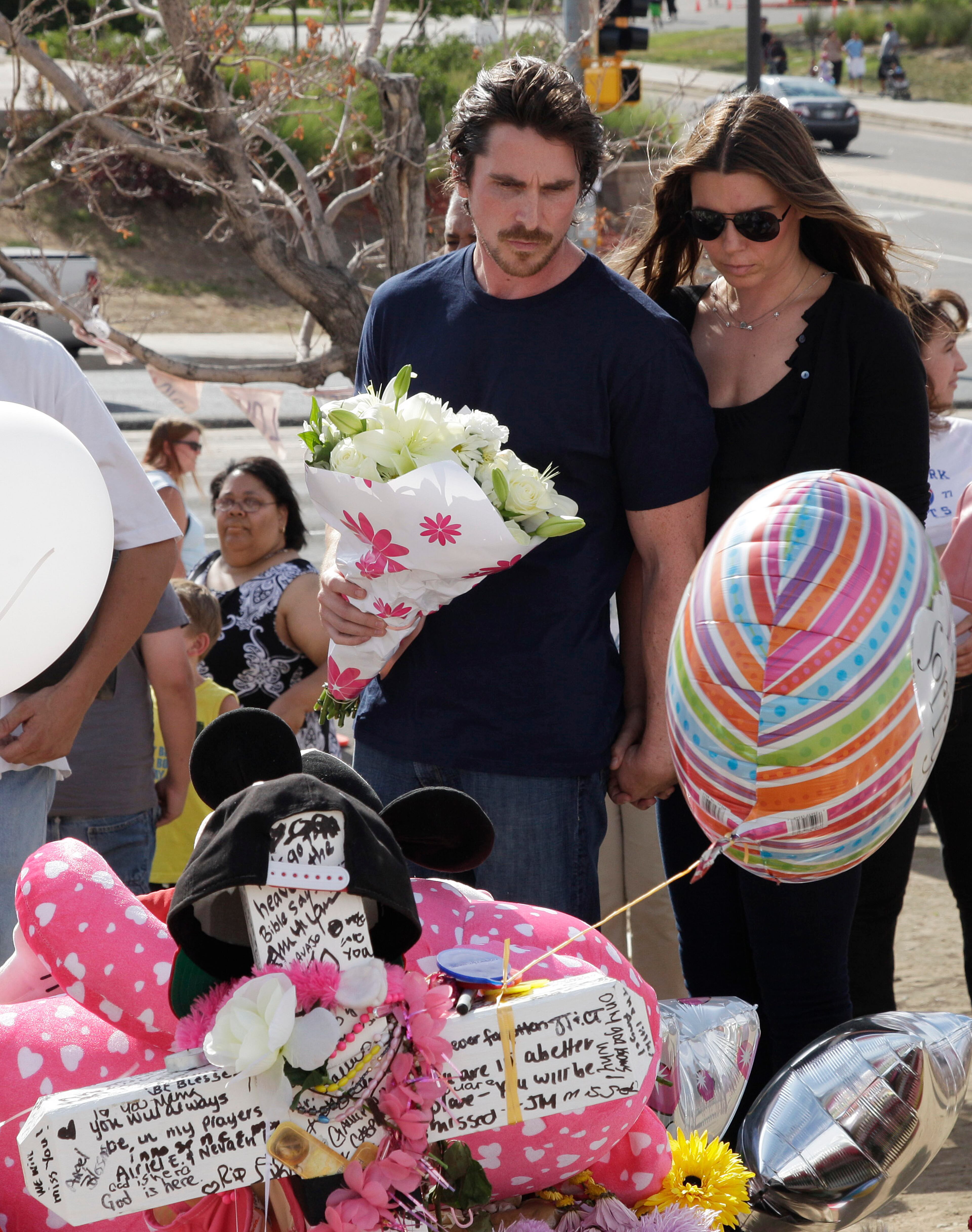 Actor Christian Bale and his wife Sibi Blazic carry flowers as they visit a memorial to the victims of Friday's mass shooting, Tuesday, July 24, 2012, in Aurora, Colo. Twelve people were killed when a gunman opened fire during a late-night showing of the movie "The Dark Knight Rises," which stars Bale as Batman. (AP Photo/Ted S. Warren)