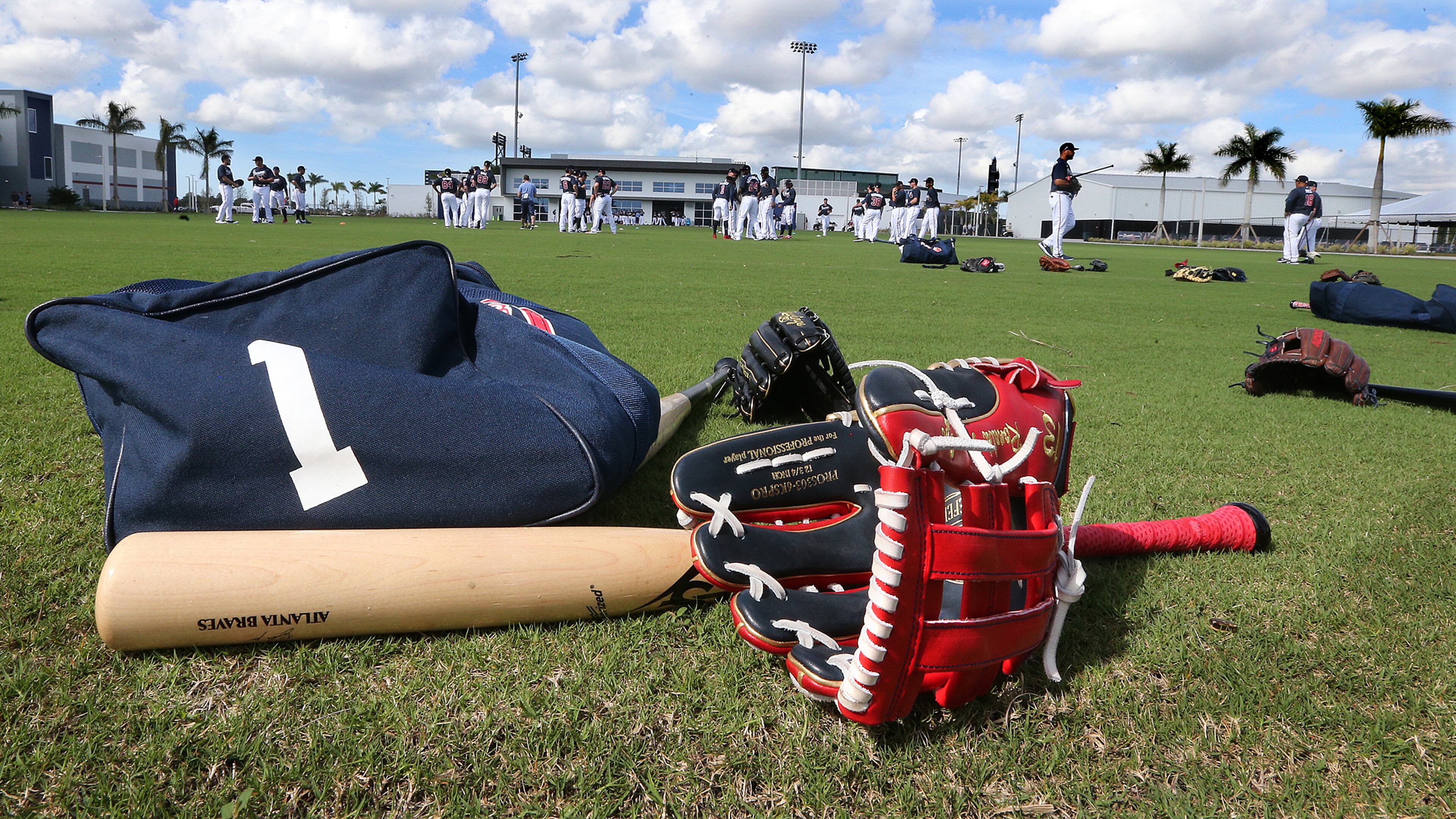 Ronald Acuna and Ozzie Albies' bats and gloves lie on the field while the Atlanta Braves team warms up for the first full squad workout Tuesday, Feb. 18, 2020, at CoolToday Park in North Port, Fla.