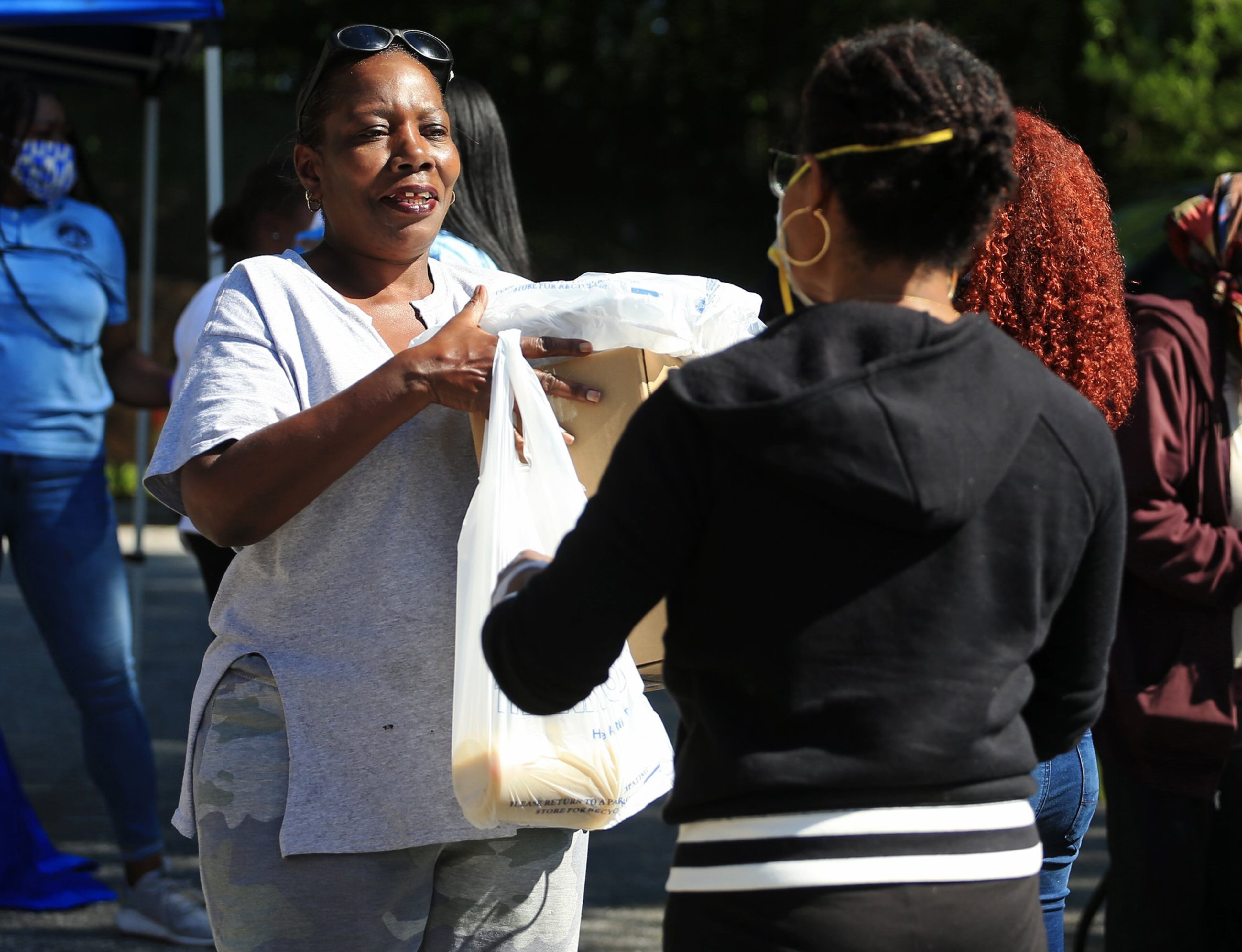 Brenda Moses receives a bag of food during the Grab and Go free food and groceries event on Friday, April 17, 2020, at Allen Hills Apartments in Atlanta, which was organized to feed families during the coronavirus pandemic. (Christina Matacotta, for The Atlanta Journal-Constitution)