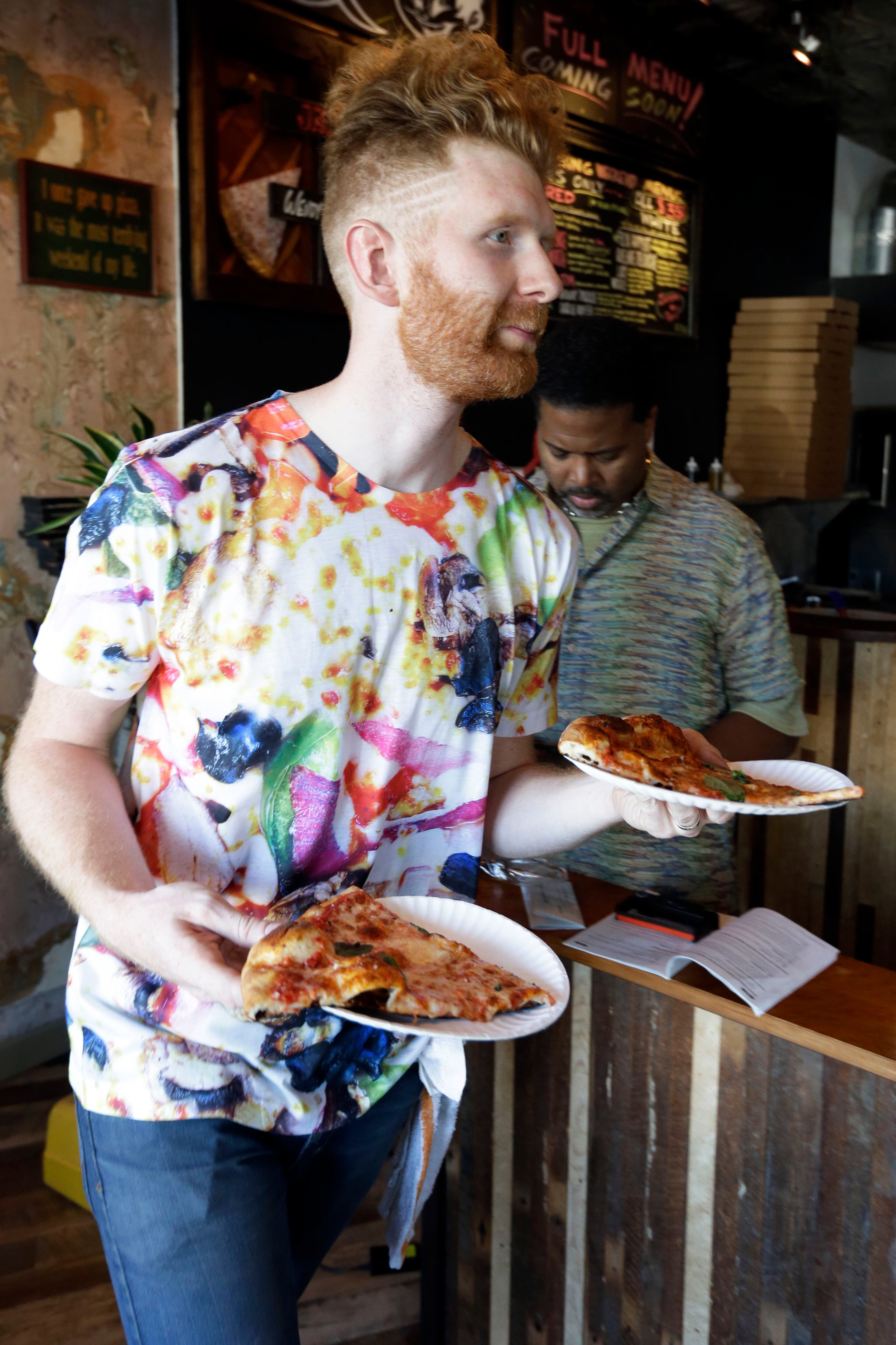 Pizza Brain's Brian Dwyer serves up an order. Visitors to the restaurant can eat a slice or two of artisan pie while gawking at pizza-related photos, records, knickknacks and videos.