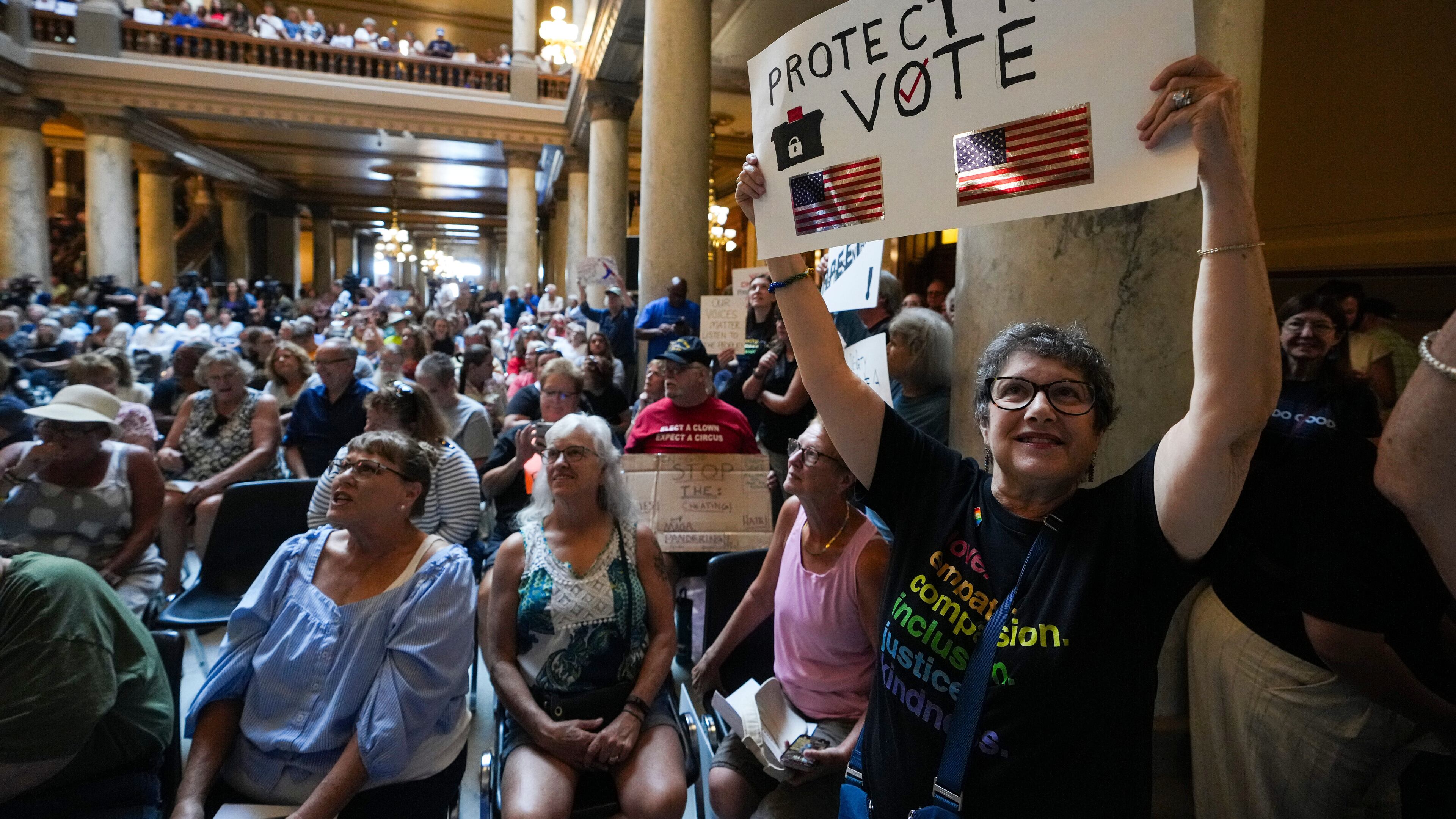 FILE - Annette Groos holds a sign before the start of a rally featuring former Transportation Secretary Pete Buttigieg at the Statehouse in Indianapolis, Thursday, Sept. 18, 2025 for Indiana Democrats amid pressure from President Donald Trump on Republicans who control the state's legislature to redistrict congressional seats. (AP Photo/Michael Conroy, File)