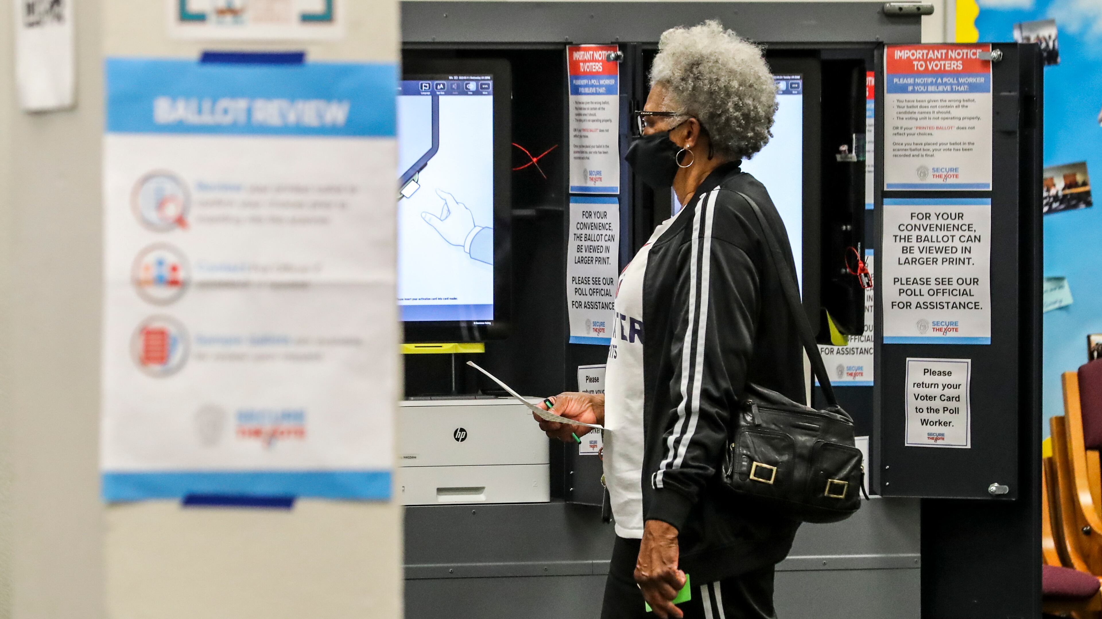 An Atlanta voter takes her ballot to be tabulated at South Atlanta High School. (John Spink / John.Spink@ajc.com)