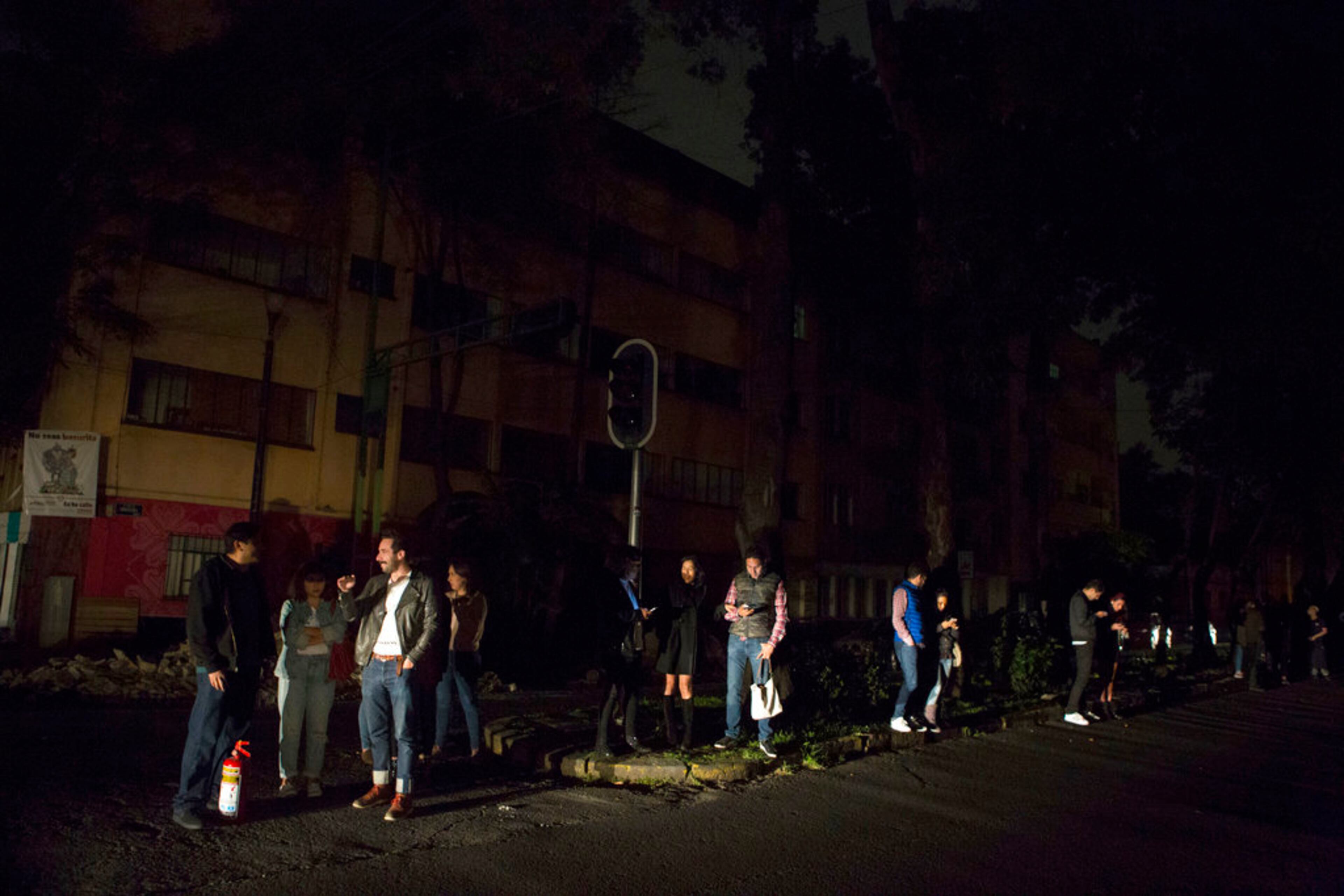 People who evacuated from bars during an earthquake stand in the street in La Roma neighborhood of Mexico City, sections of which lost power, just before midnight on Thursday, Sept. 7, 2017. (AP Photo/Rebecca Blackwell)