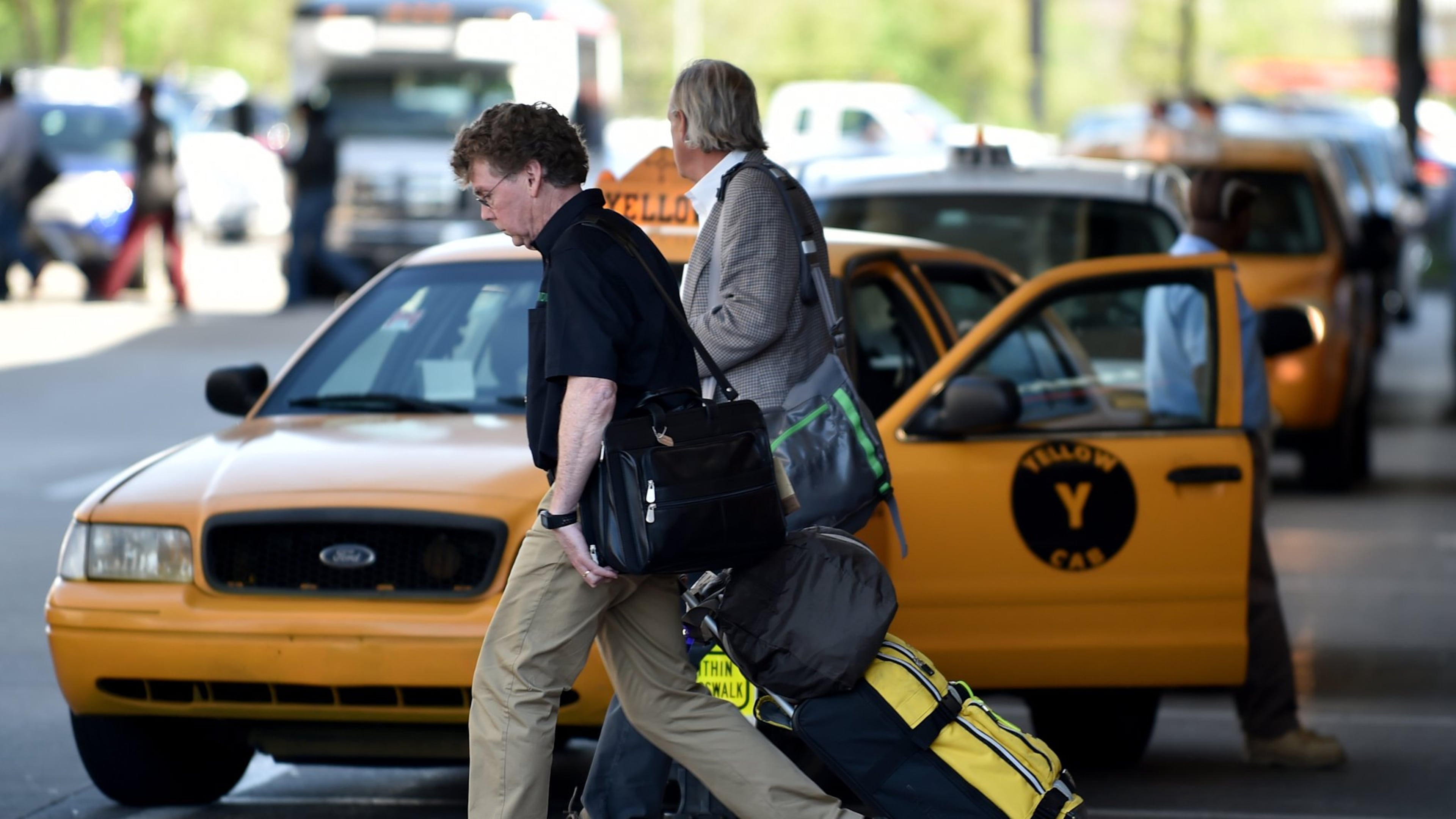 Arriving travelers walk past a taxi at Hartsfield Jackson International Airport. Some are bypassing traditional transportation such as taxis and shuttles, opting for social media-based ride services such as Uber. BRANT SANDERLIN/BSANDERLIN@AJC.COM
