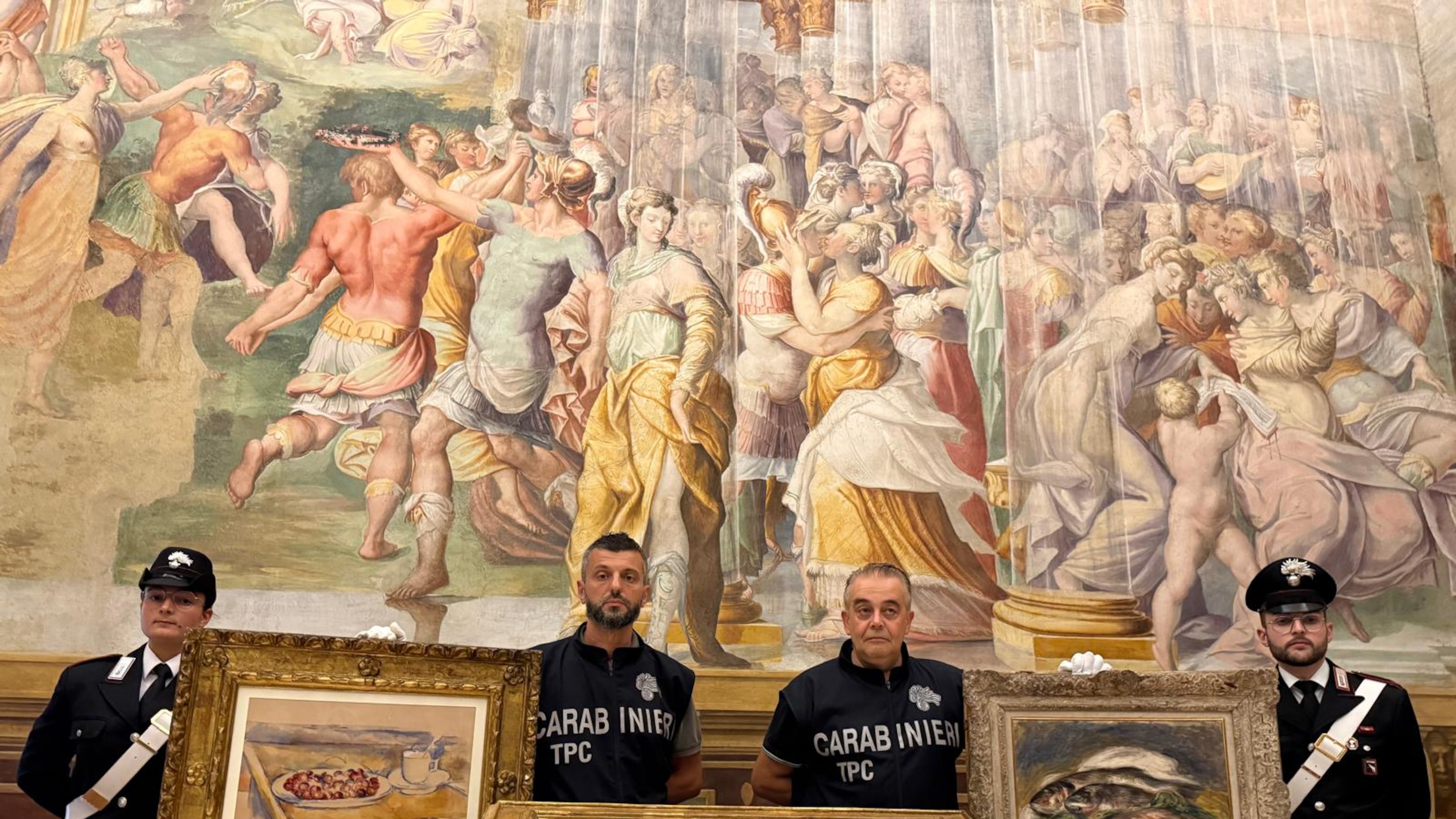 In this picture made available by the Italian Carabinieri in Parma, northern Italy, Friday, Aug. 14, 2026, Carabinieri pose near three paintings recovered following a police operation: "Tasse et plat de cerises" by Paul Cezanne, left, "Odalisque Sur La Terrasse" by Henri Matisse, center, and "Les Poissons" by Pierre Auguste Renoir, right. (Italian Carabinieri via AP)