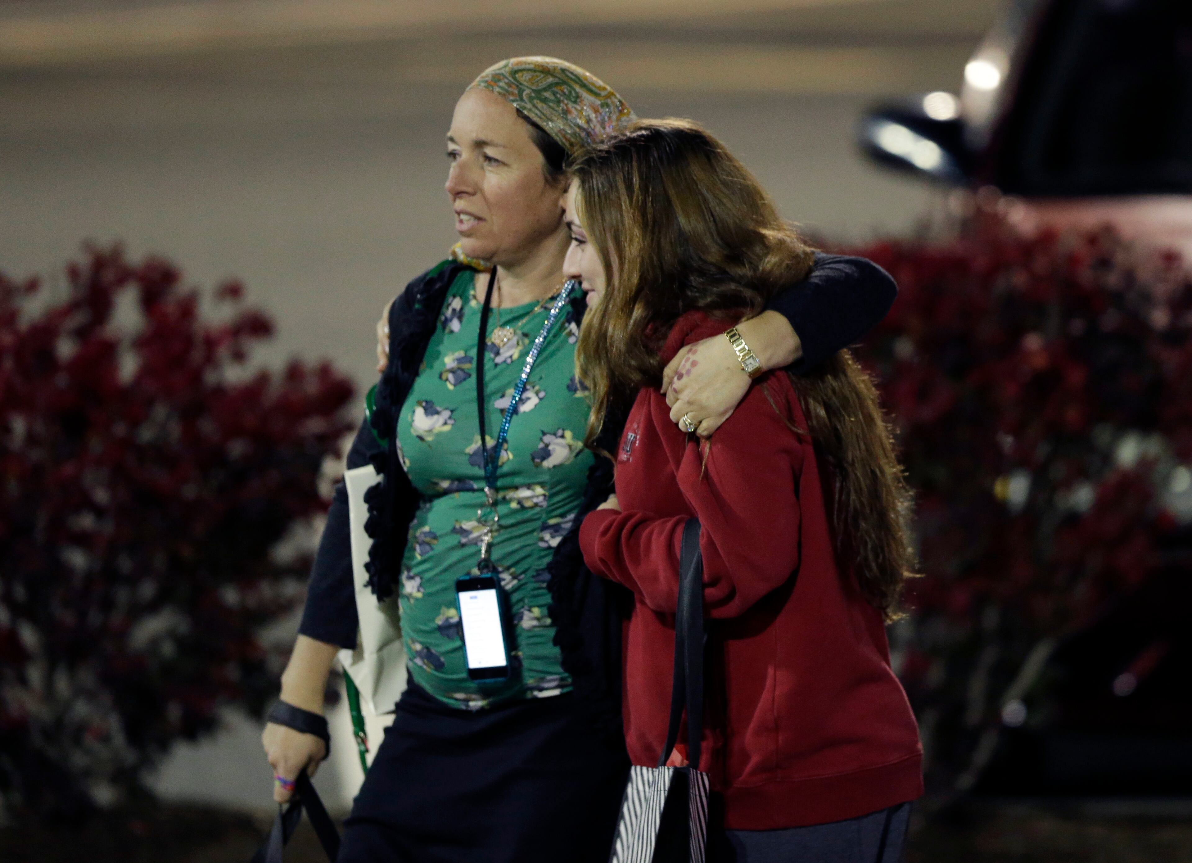 Two women walk in the parking lot of the Garden State Plaza Mall with officials standing guard following reports of a shooter, Monday, Nov. 4, 2013, in Paramus, N.J. Hundreds of law enforcement officers converged on the mall Monday night after witnesses said multiple shots were fired there. (AP Photo/Julio Cortez)