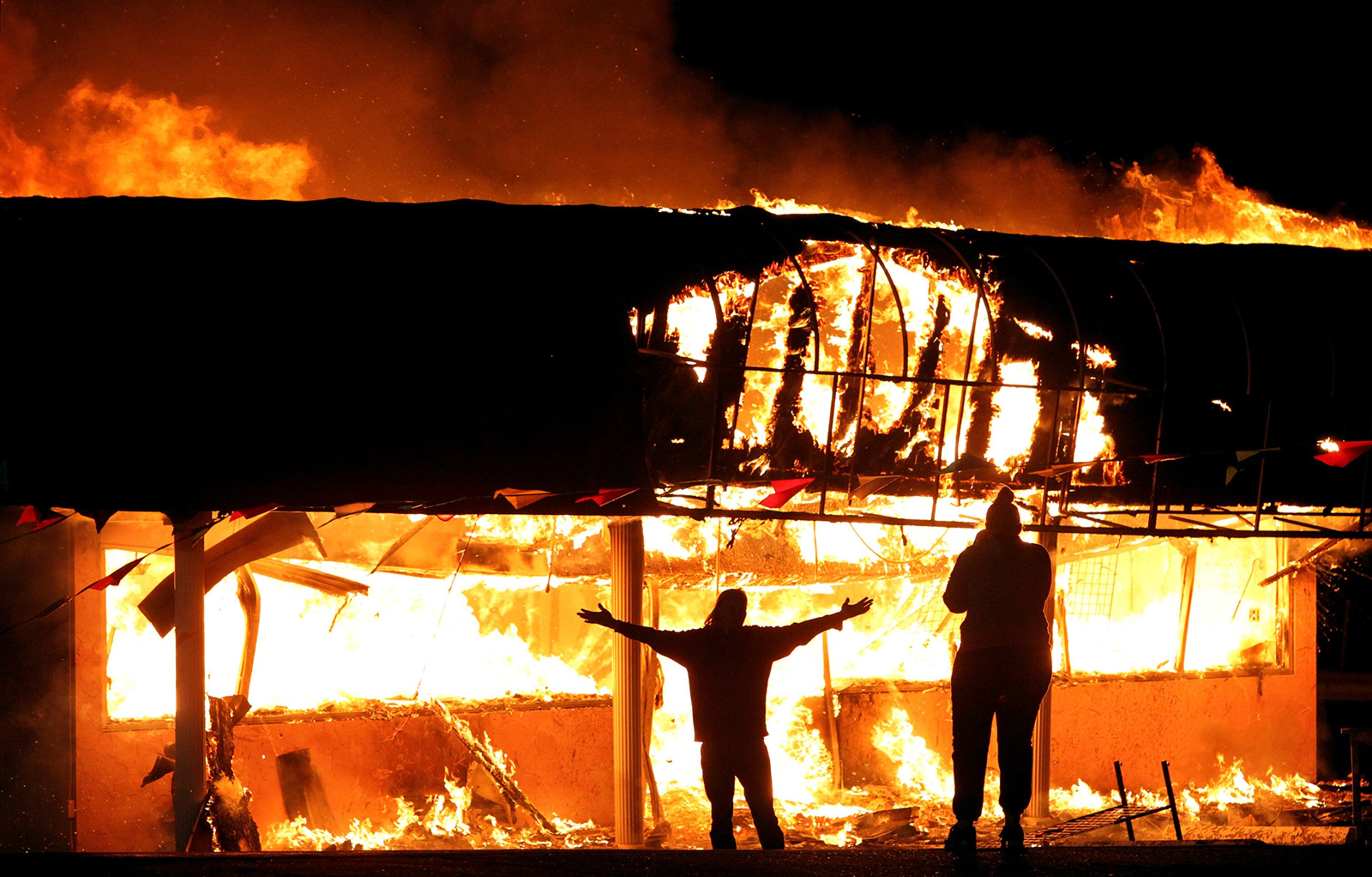 Protesters take their pictures in front of the burning Juanita's Fashion R Boutique on West Florissant Avenue in St. Louis, Mo. early Tuesday, Nov. 25, 2014. Protesters set fire to buildings and cars and loot businesses in the area where Michael Brown was fatally shot after a grand jury declined to indict white police officer Darren Wilson in the death of the unarmed, black 18-year-old. (AP Photo/St. Louis Post-Dispatch, Robert Cohen)