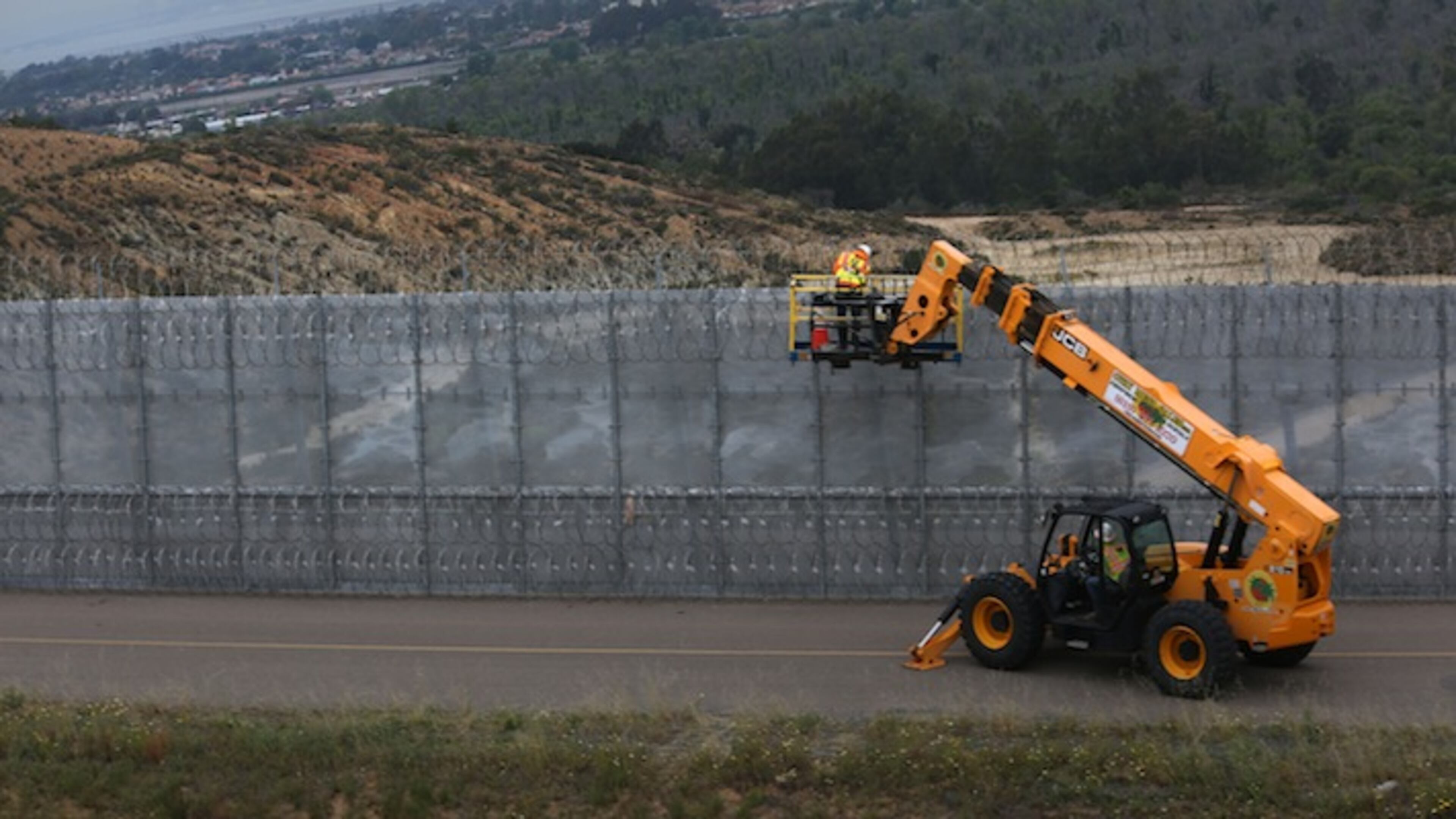 Seen from Tijuana, Border Patrol crews work on the consertina wire atop the secondary fence in the area near the water treatment plant Wednesday, May 9, 2016. (Peggy Peattie/San Diego Union-Tribune/TNS)