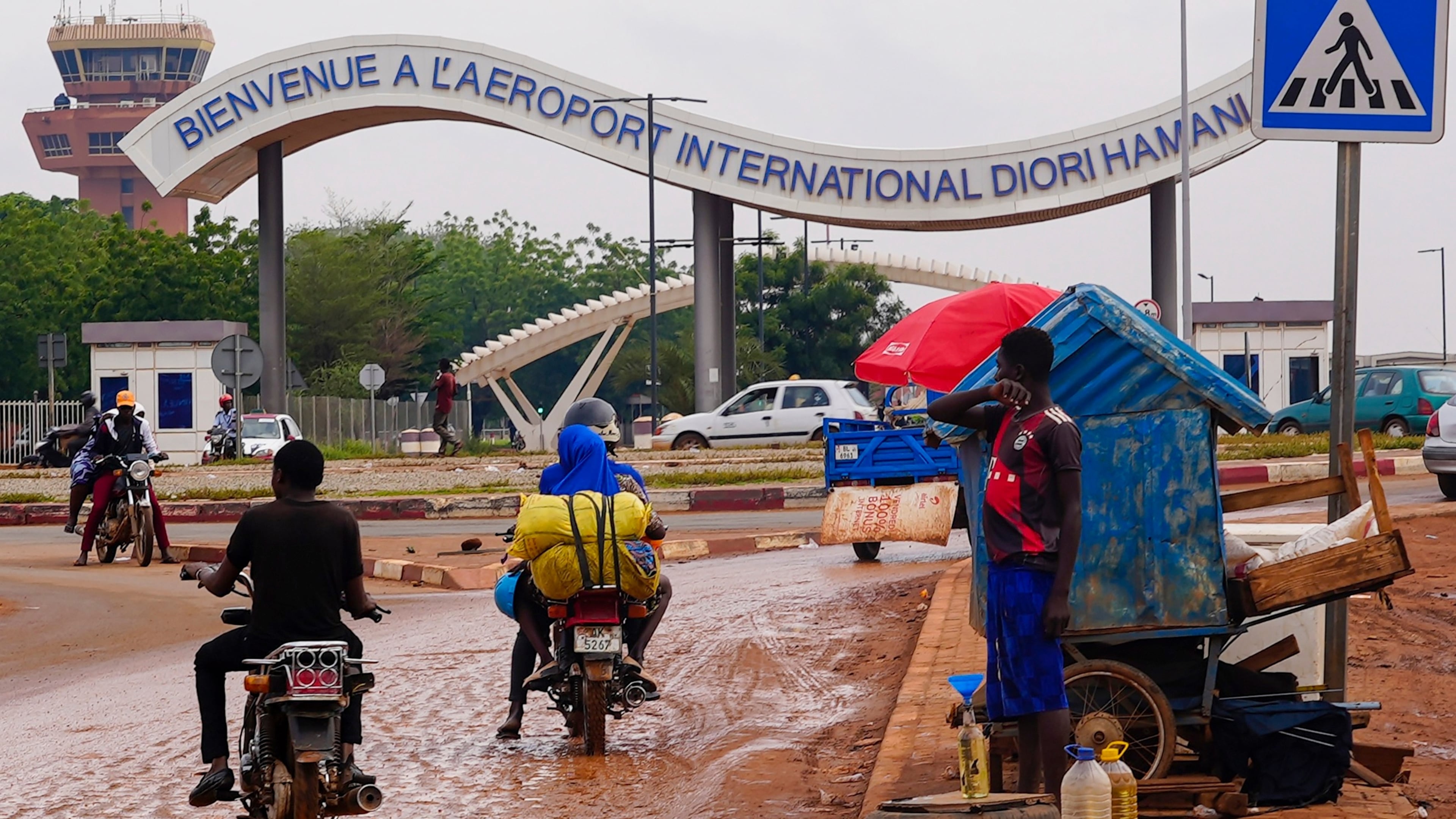 FILE- Motorcyclists ride by the entrance of the airport in Niamey, Niger, Aug. 8, 2023. (AP Photo/Sam Mednick, File)
