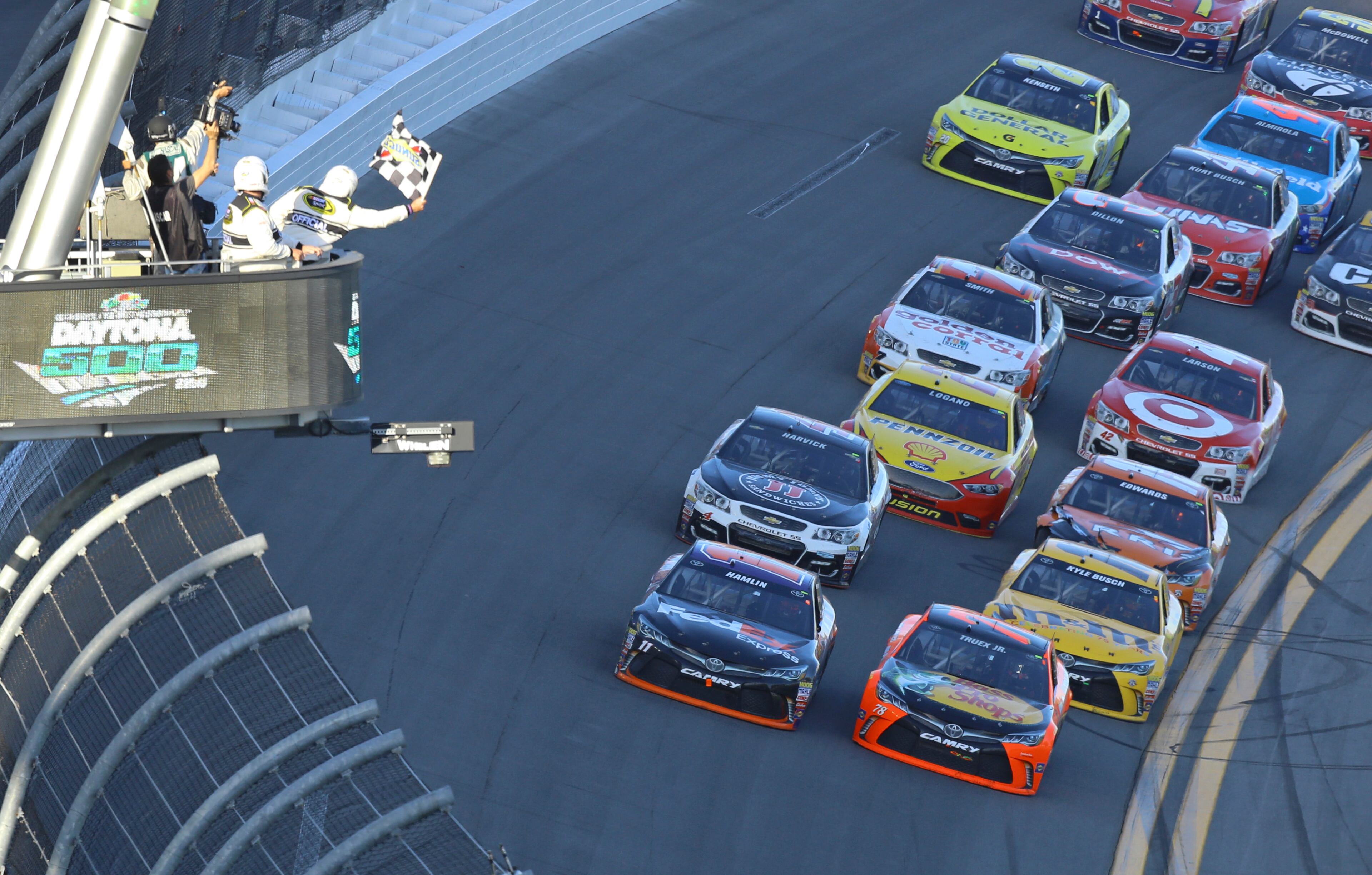 Denny Hamlin, left, and Martin Truex Jr, right, race to the checkered flag on the last lap of the NASCAR Daytona 500 Sprint Cup Series auto race at Daytona International Speedway in Daytona Beach, Fla., Sunday, Feb. 21, 2016. (AP Photo/David Graham)