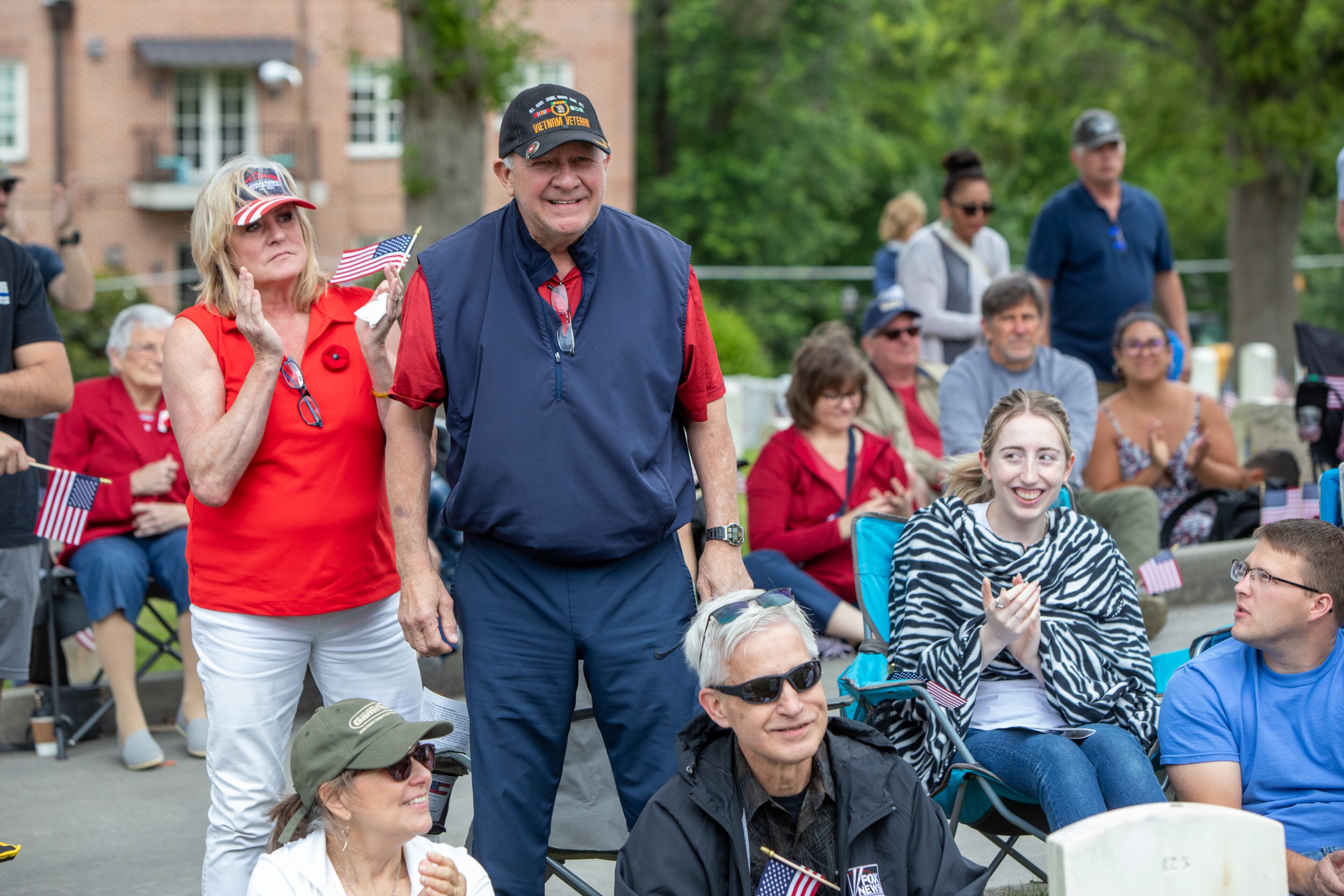 Standing for the Armed Forces Medley and representing the Marines, Julie Porter, left, supports her veteran Marine husband, Ken Porter, during the 77th annual Memorial Day Observance at the Marietta National Cemetery on Monday, May 29, 2003. (Jenni Girtman for The Atlanta Journal-Constitution)