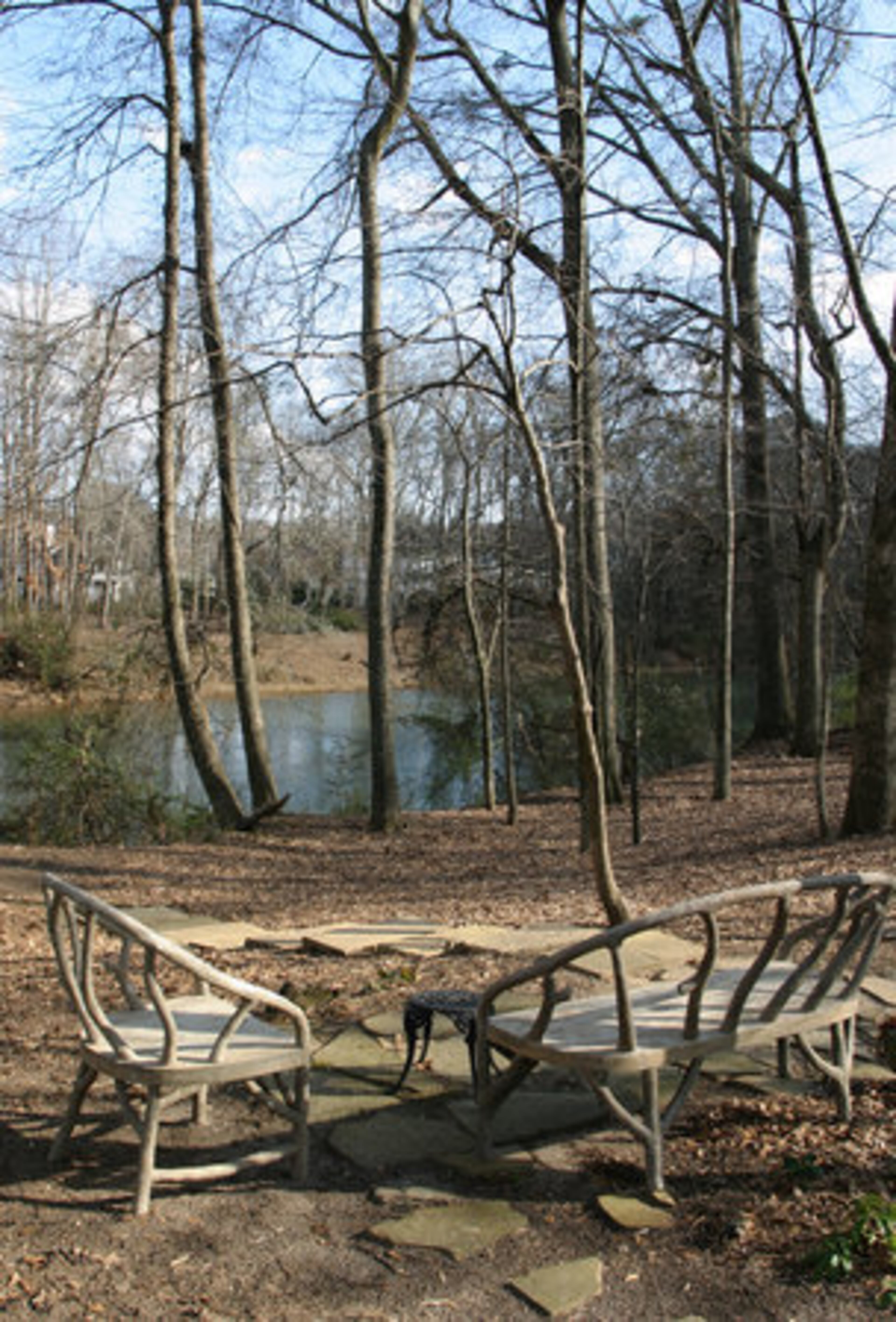 A path, made from Tennessee flagstone, leads from the sunroom to this clearing by the Chattahoochee River. Faux bois furniture (French for "fake wood") offers an elegant spot for rest and introspection.