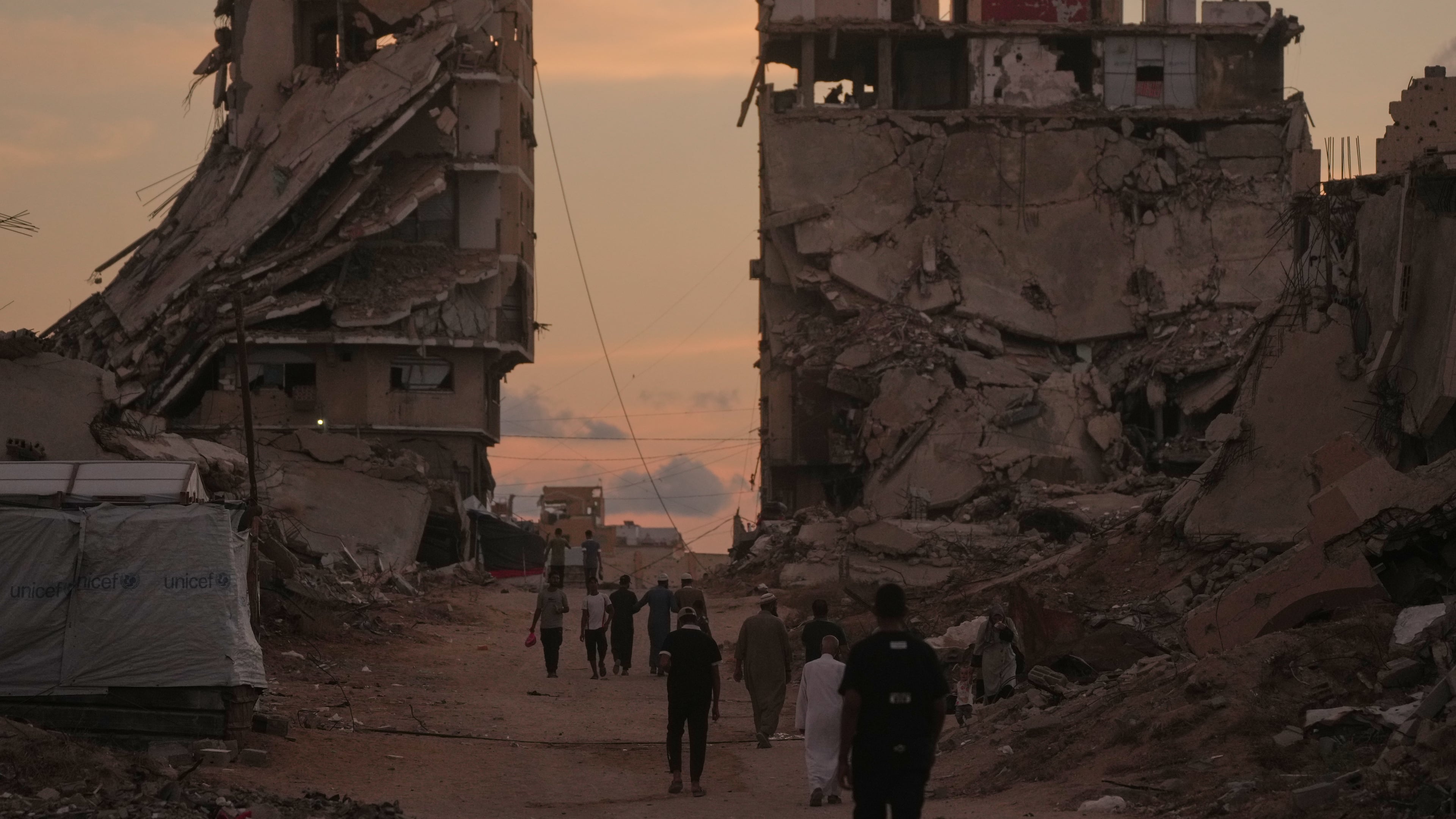 Palestinians walk along a street surrounded by buildings destroyed in Israeli military strikes during the Israel-Hamas war in Gaza City, Tuesday, Oct. 6, 2026. (AP Photo/Jehad Alshrafi)