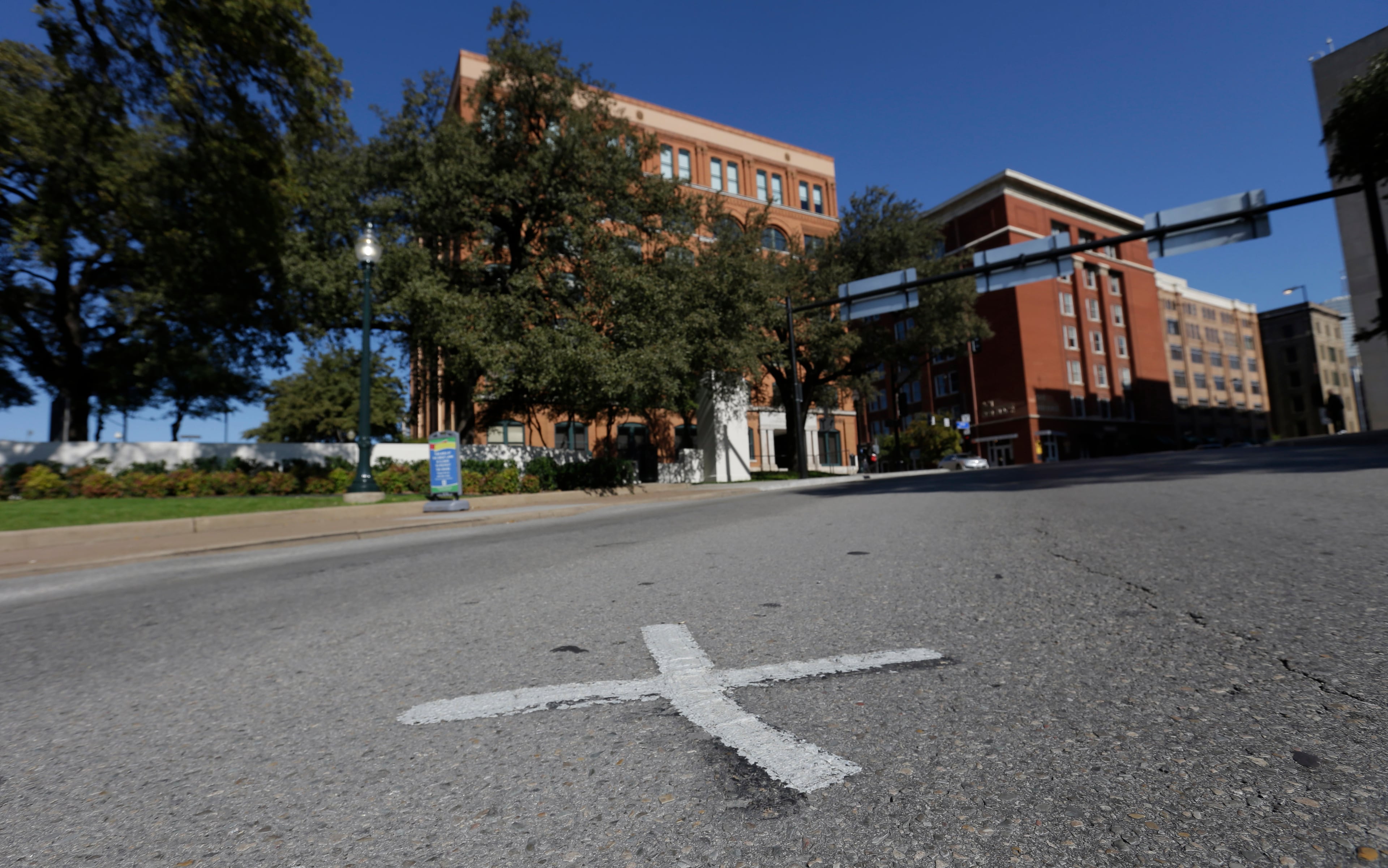 An X marks the spot on Elm Street on Tuesday in 2013 where the first bullet hit President John F. Kennedy on Nov. 22, 1963 near the former Texas School Book Depository, now known as the Sixth Floor Museum, background, on Dealey Plaza in Dallas. (AP Photo/LM Otero)