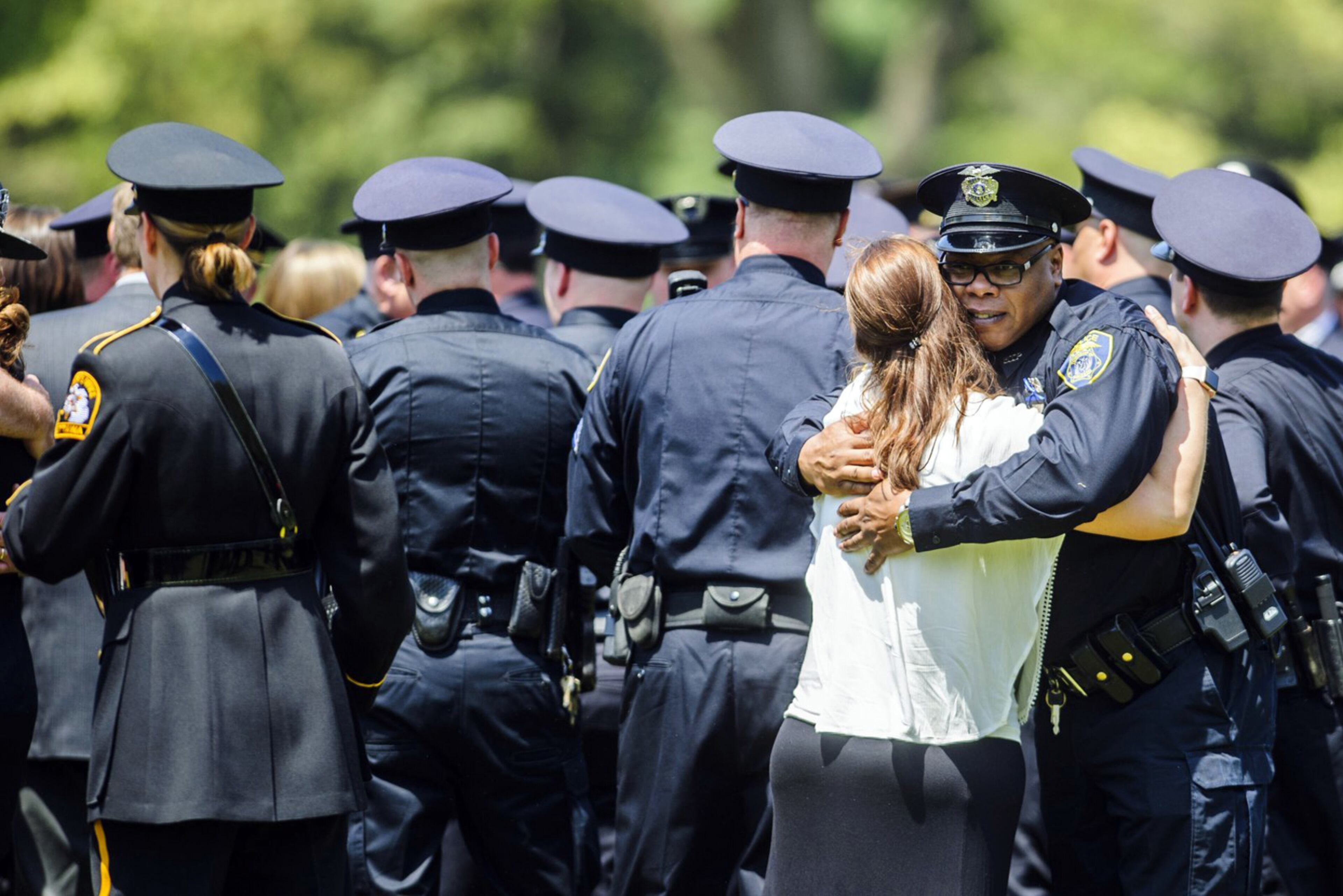A police officer hugs a woman during the funeral for Norton Shores police officer Jonathan Ginka on Tuesday, May 16, 2017 in North Muskegon, Mich. Ginka was killed after his police cruiser struck a tree in the early morning hours of May 10 along Henry Street between Ross and Forest Park Roads in Norton Shores. (Kaytie Boomer /Muskegon Chronicle via AP)
