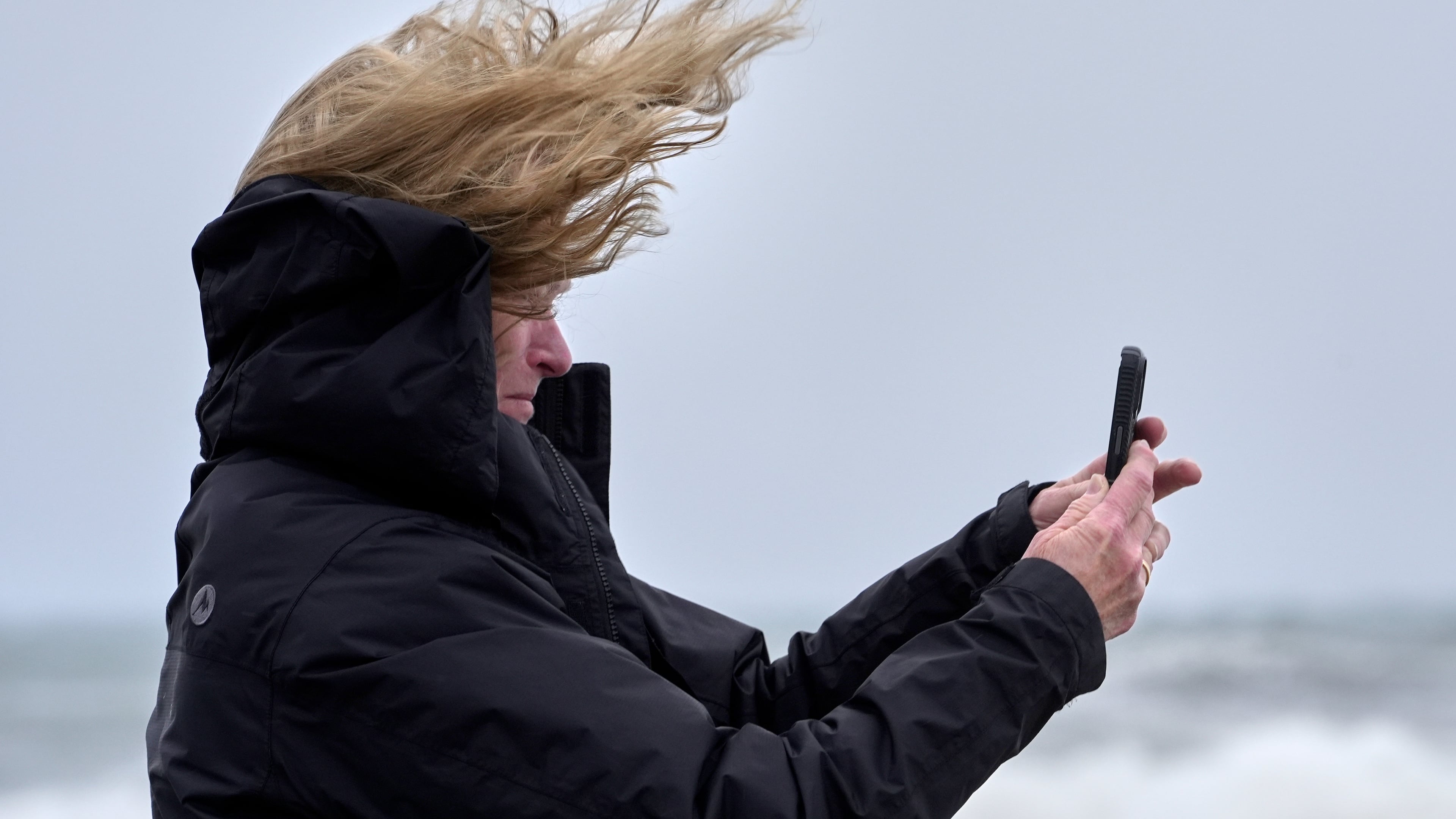 Denise Taylor of Manchester, N.H., is buffeted by the wind as she films the raging sea during a nor'easter storm in Hampton, N.H., Saturday, Sept. 26, 2026. (AP Photo/Robert F. Bukaty)