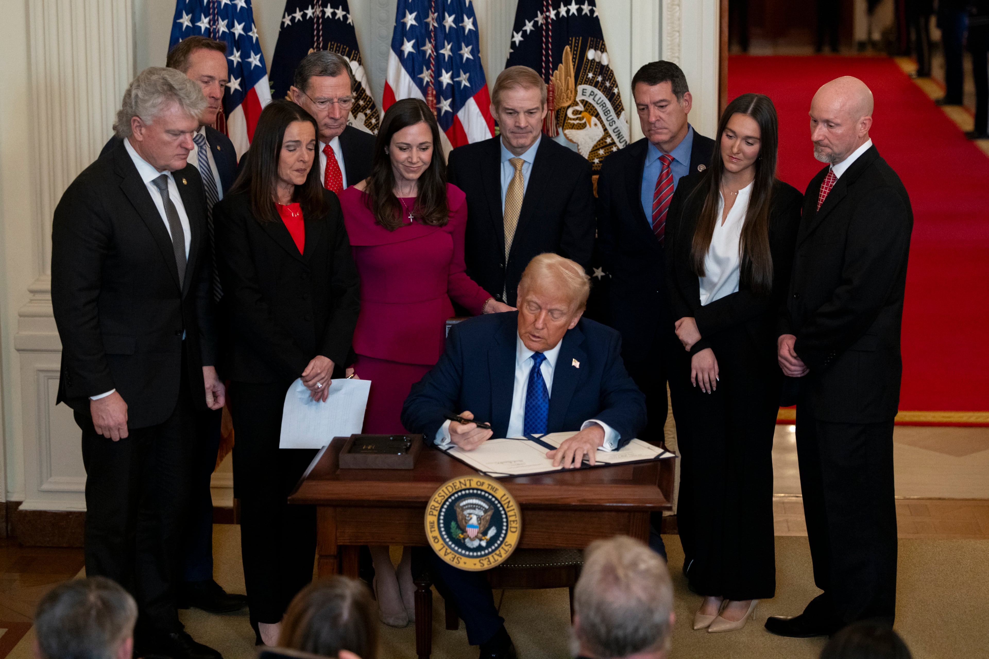 President Donald Trump, surrounded by members of Congress and Laken Riley’s family, signs the Laken Riley Act on Jan. 29. (Nathan Posner for the AJC)