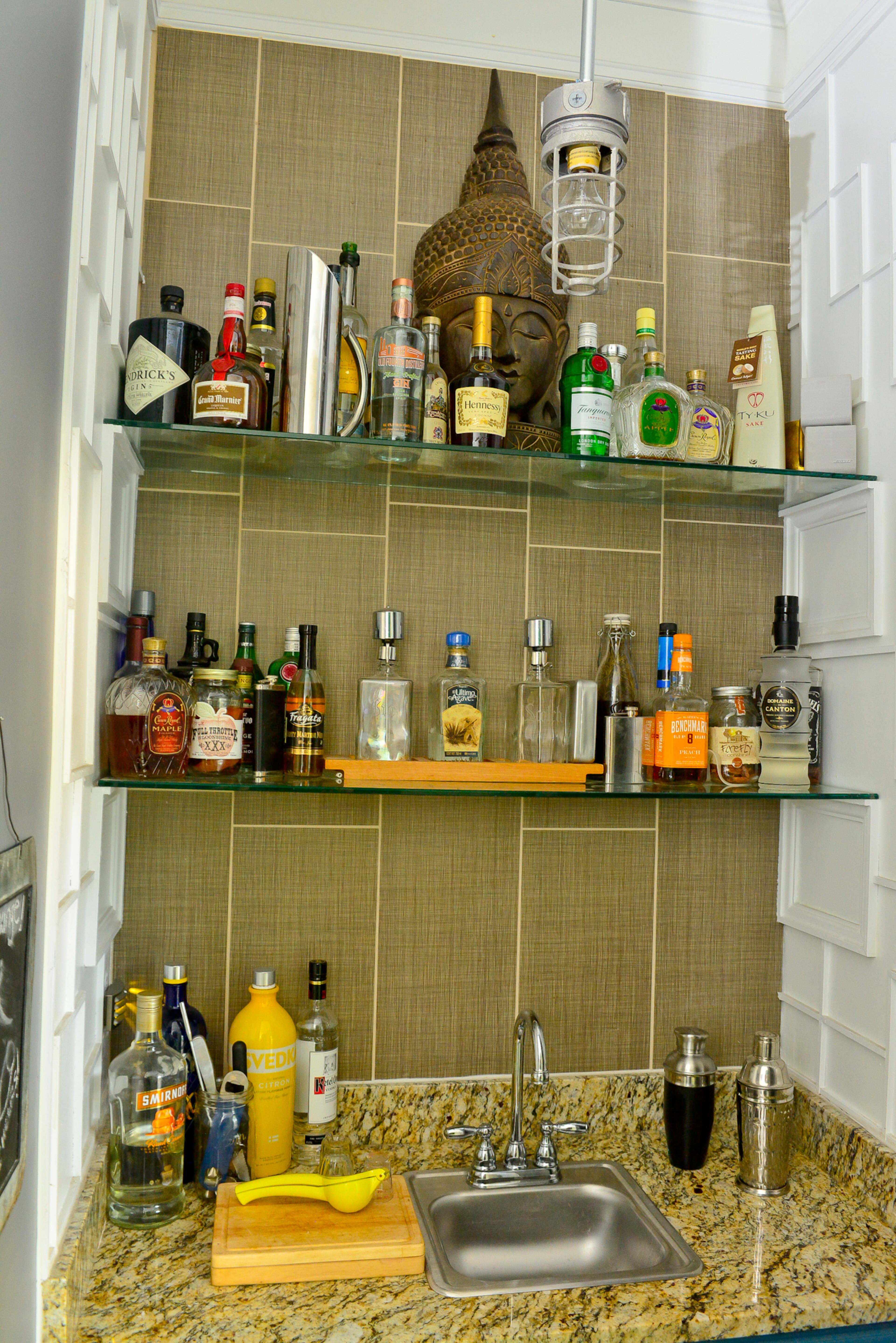 What once served as a closet in Walker and McNeal's 1908 Craftsman home now serves libations to the homeowners and their guests. The wet bar's detailed molding, granite counter and vertical tiles work with the glass shelving to make a bold statement in a small space.