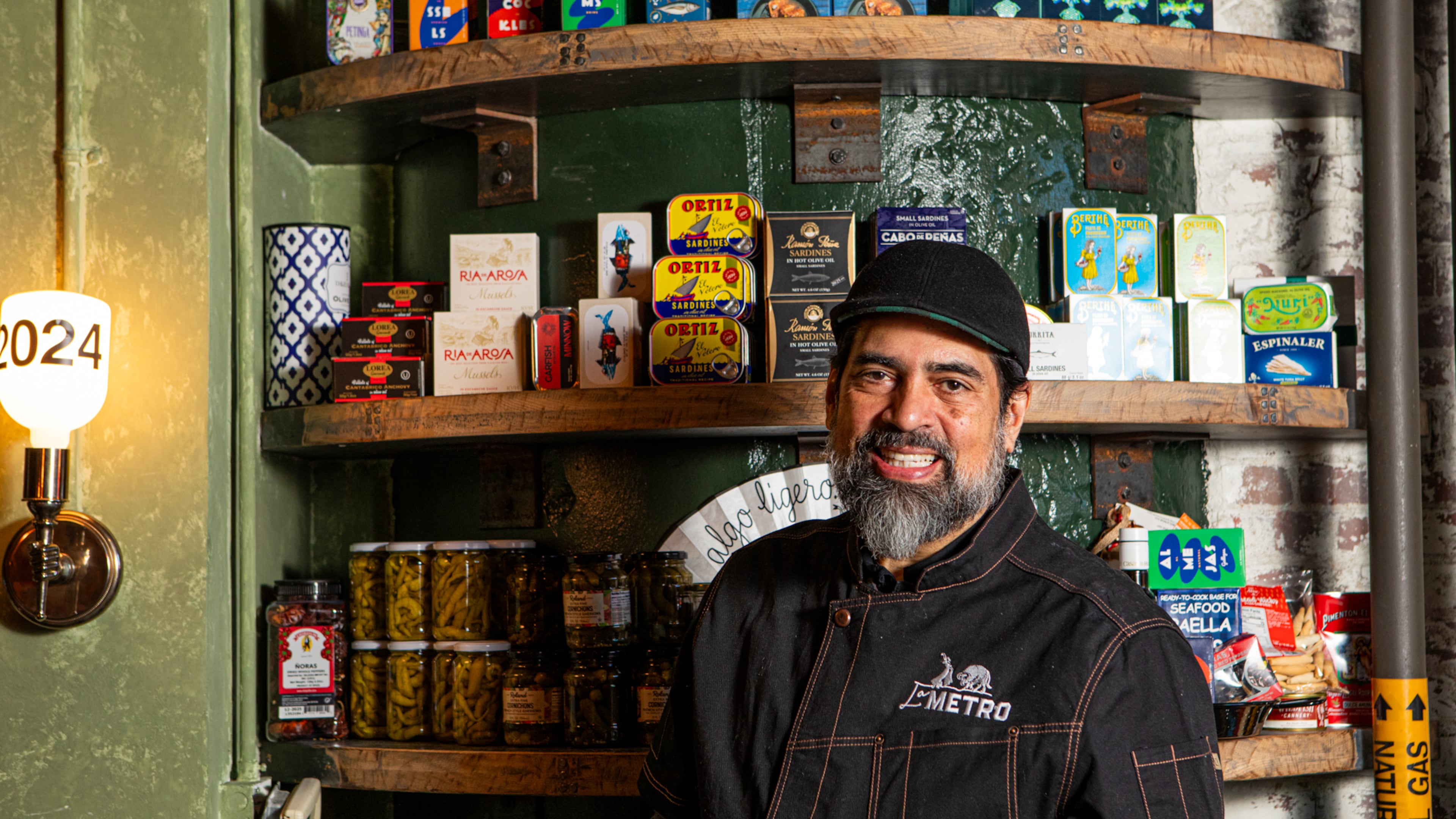 Hector Santiago, chef-owner of Spanish tapas restaurant La Metro at Ponce City Market, stands near a display of tinned seafood that is available for retail purchase. (Aaliyah Man for The Atlanta Journal-Constitution)