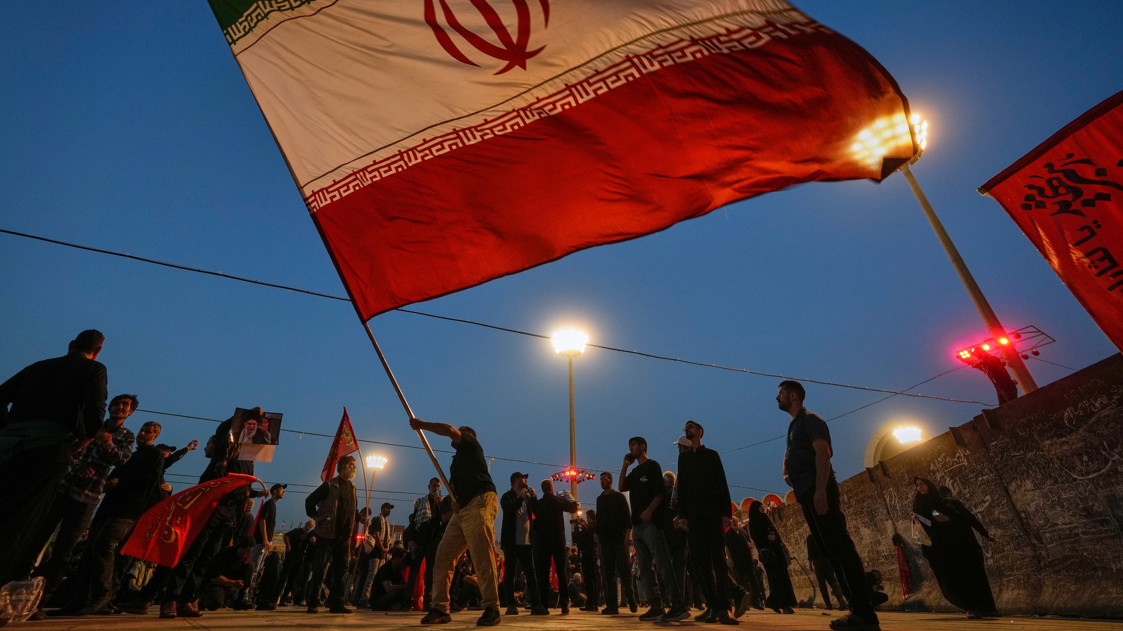 A man waves an Iranian flag during funeral ceremonies for slain Iranian Supreme Leader Ayatollah Ali Khamenei and members of his family at Imam Khomeini Mosalla Grand Mosque in Tehran, Iran, Sunday, July 5, 2026. (AP Photo/Altaf Qadri)