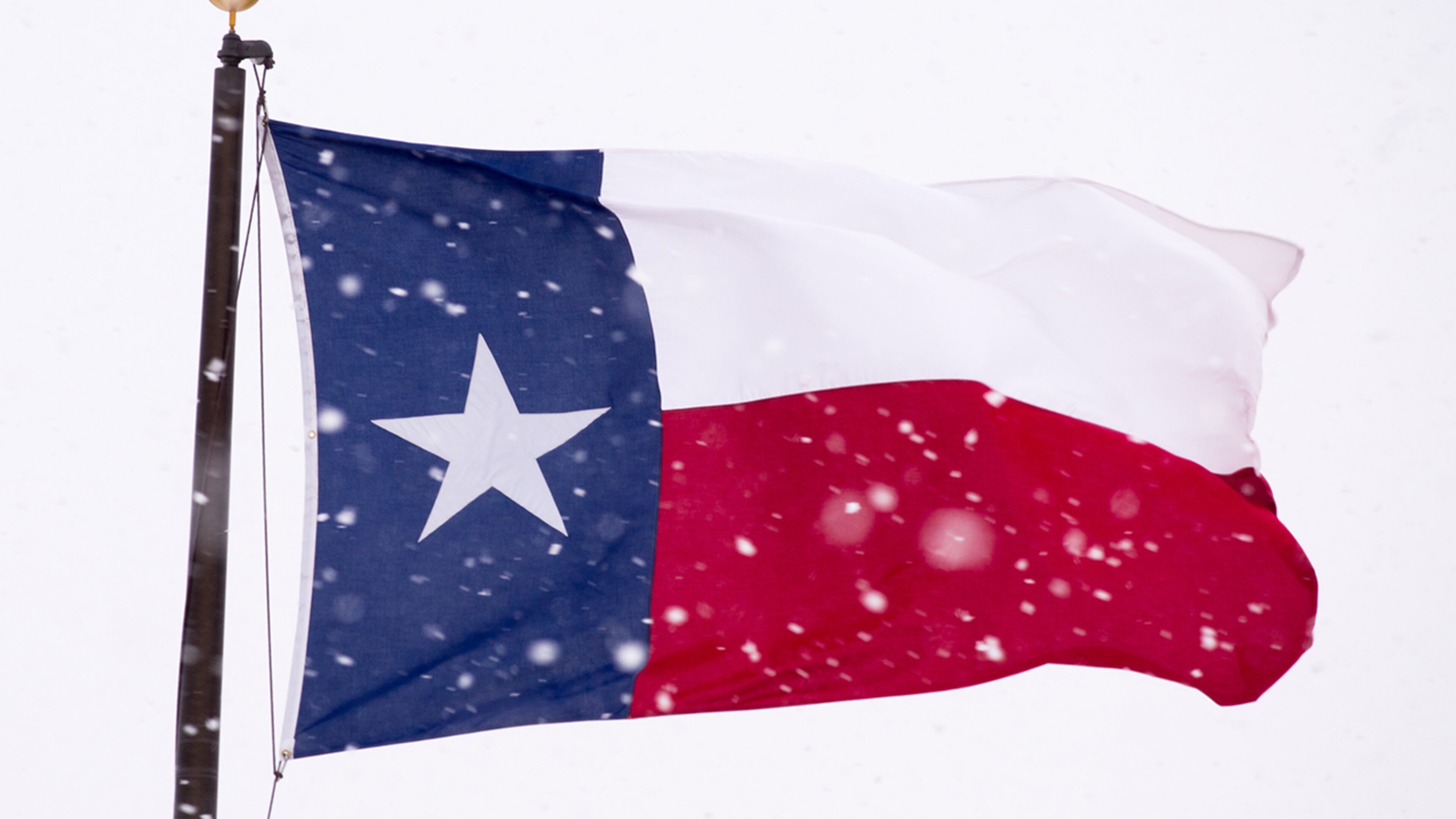 LUBBOCK, TEXAS - DECEMBER 27: The Texas state flag is battered by high wind and heavy snow on December 27, 2015 in Lubbock, Texas. Coming on the heels of several strong tornadoes, some northern parts of Texas are experiencing blizzard conditions with wind gusts up to 50 mph and as much as 13 inches of snow forecast. (Photo by John Weast/Getty Images)