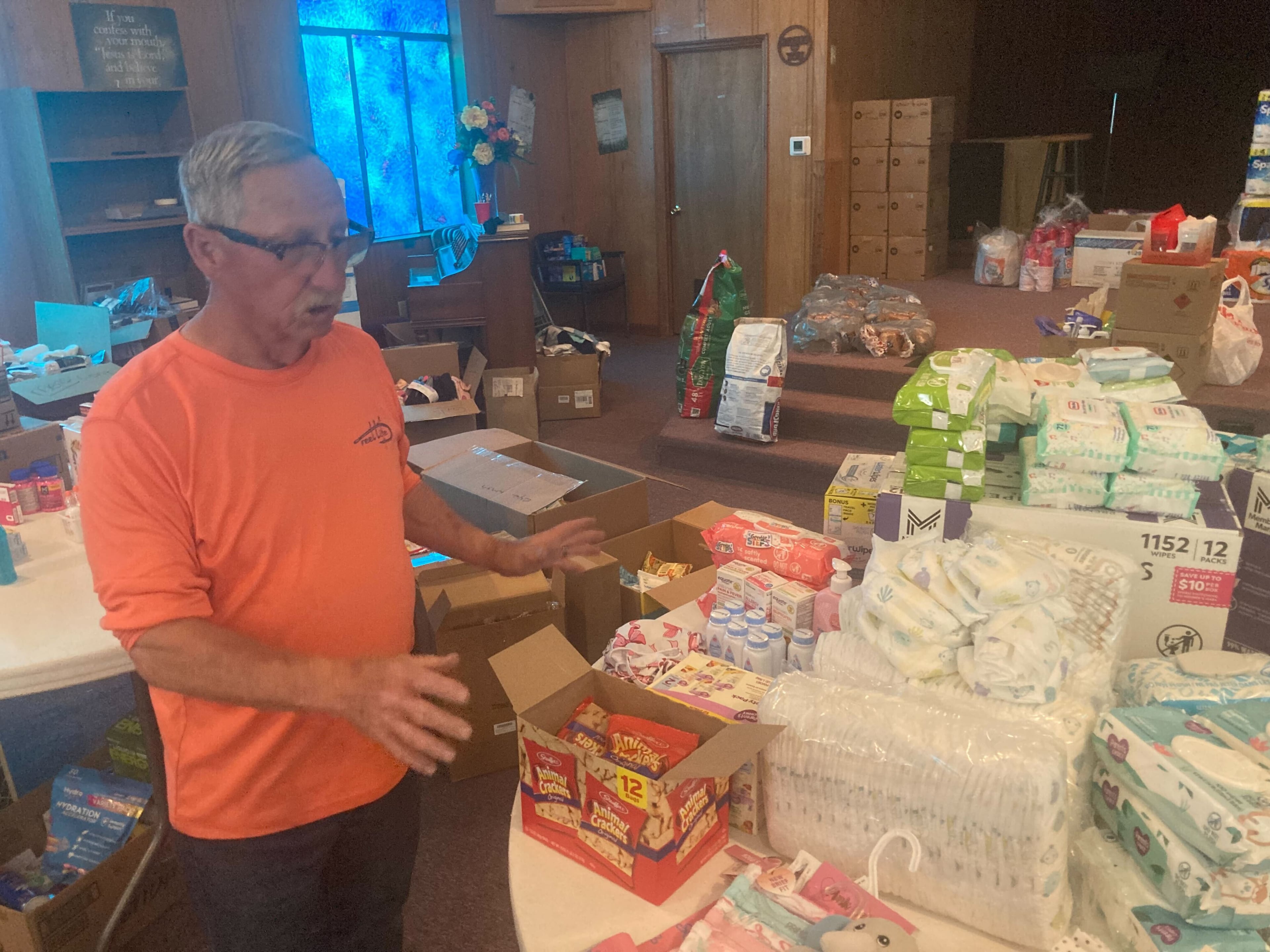 Deacon Ron Olmstead helps organize food supplies on Friday at Waynesville Missionary Baptist Church in Brantley County for residents affected by the Highway 82 wildfire that has destroyed about 90 homes. He says flames came within a mile of his home before the wind shifted, helping save it. “Ash was falling in my yard like snow,” he said. (Adam Van Brimmer/AJC)