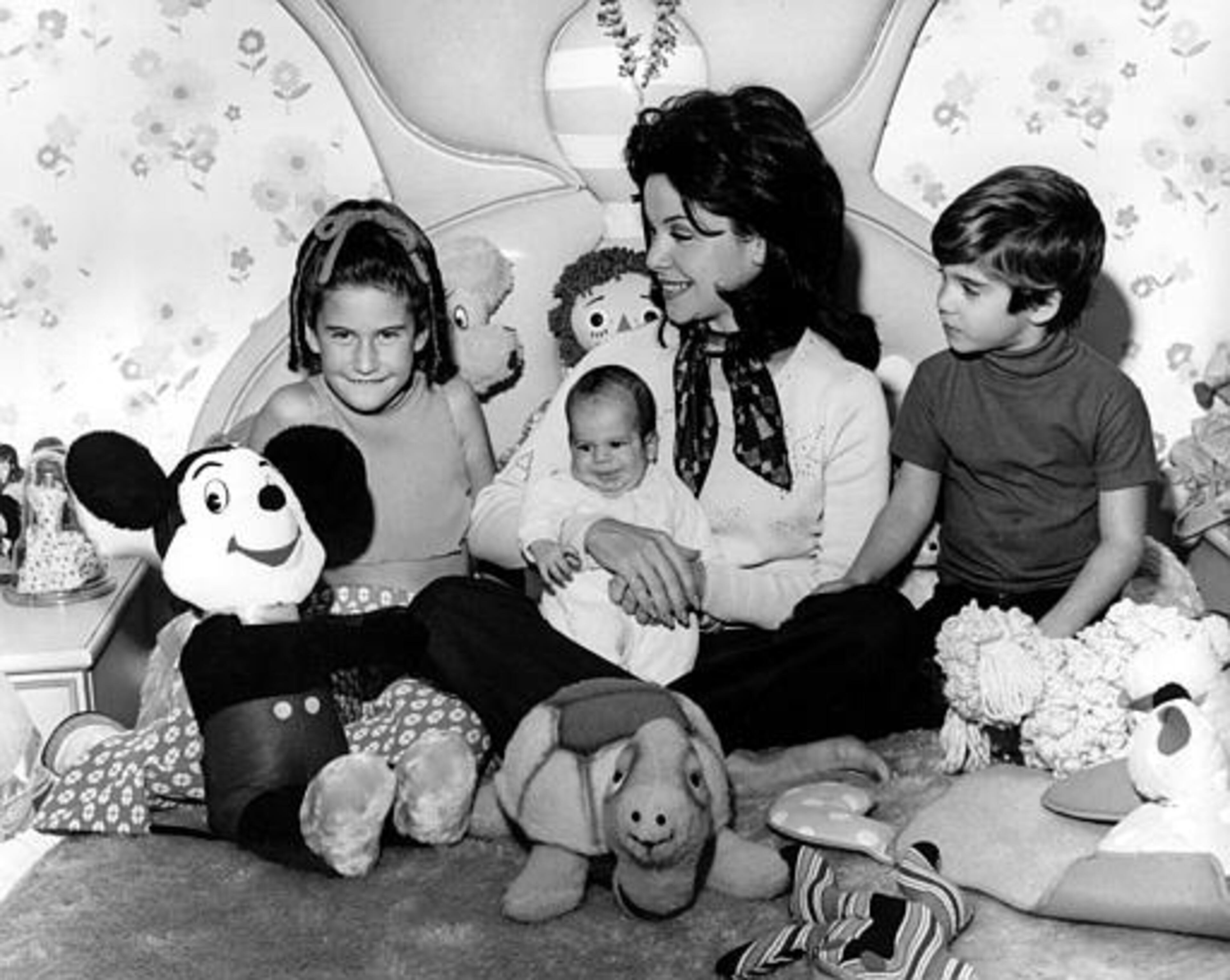 Actress and former Mouseketeer Annette Funicello holds her infant son, 7-month-old Jason, while watching a revival TV show of the old Mickey Mouse Club series with 9-year-old daughter Gina, and 5-year-old son Jack Jr., at her home in Burbank, Calif., on March 11, 1975. (AP Photo)