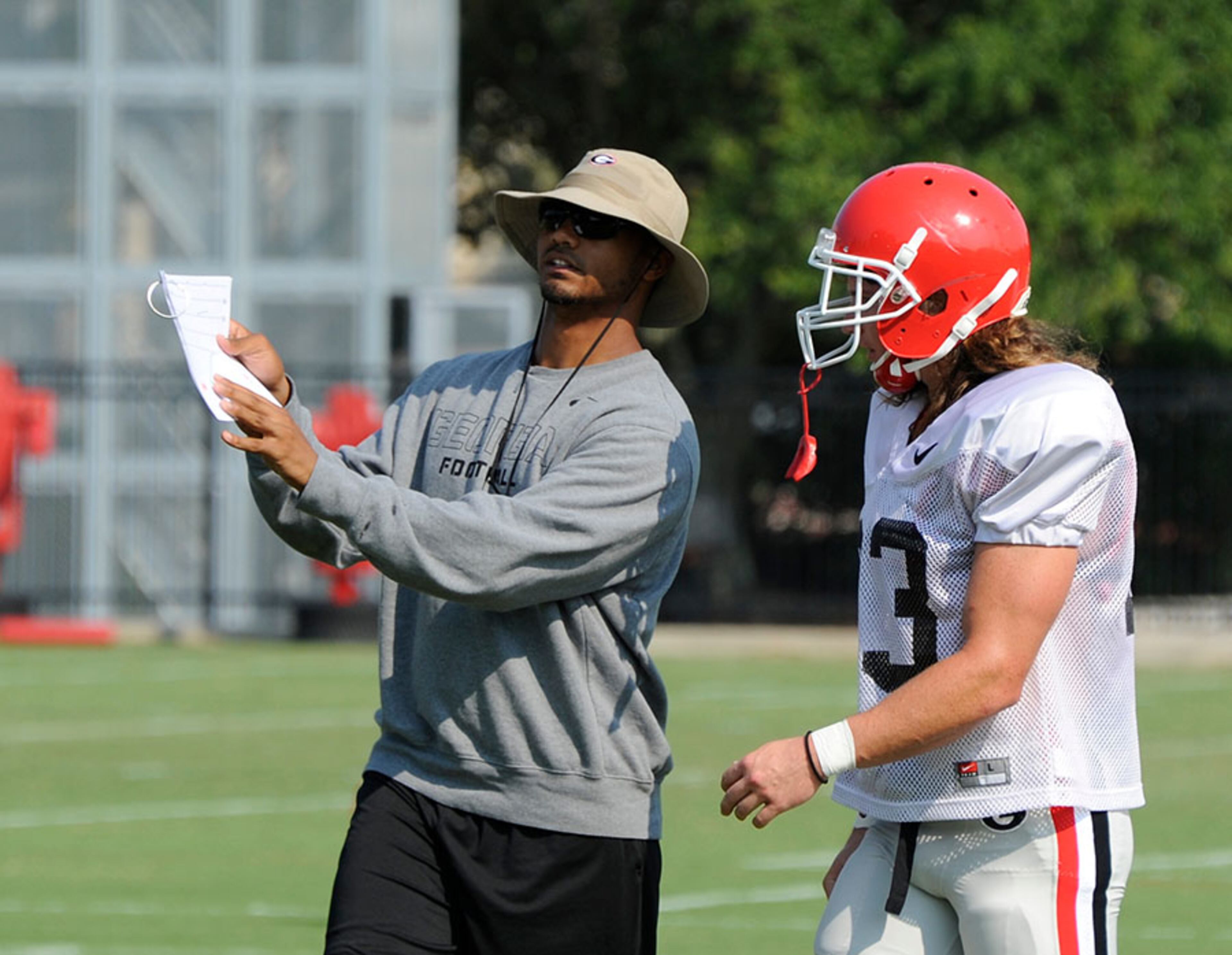 Graduate assistant Christian Robinson (left) points out a play during Georgia's morning practice in Athens.