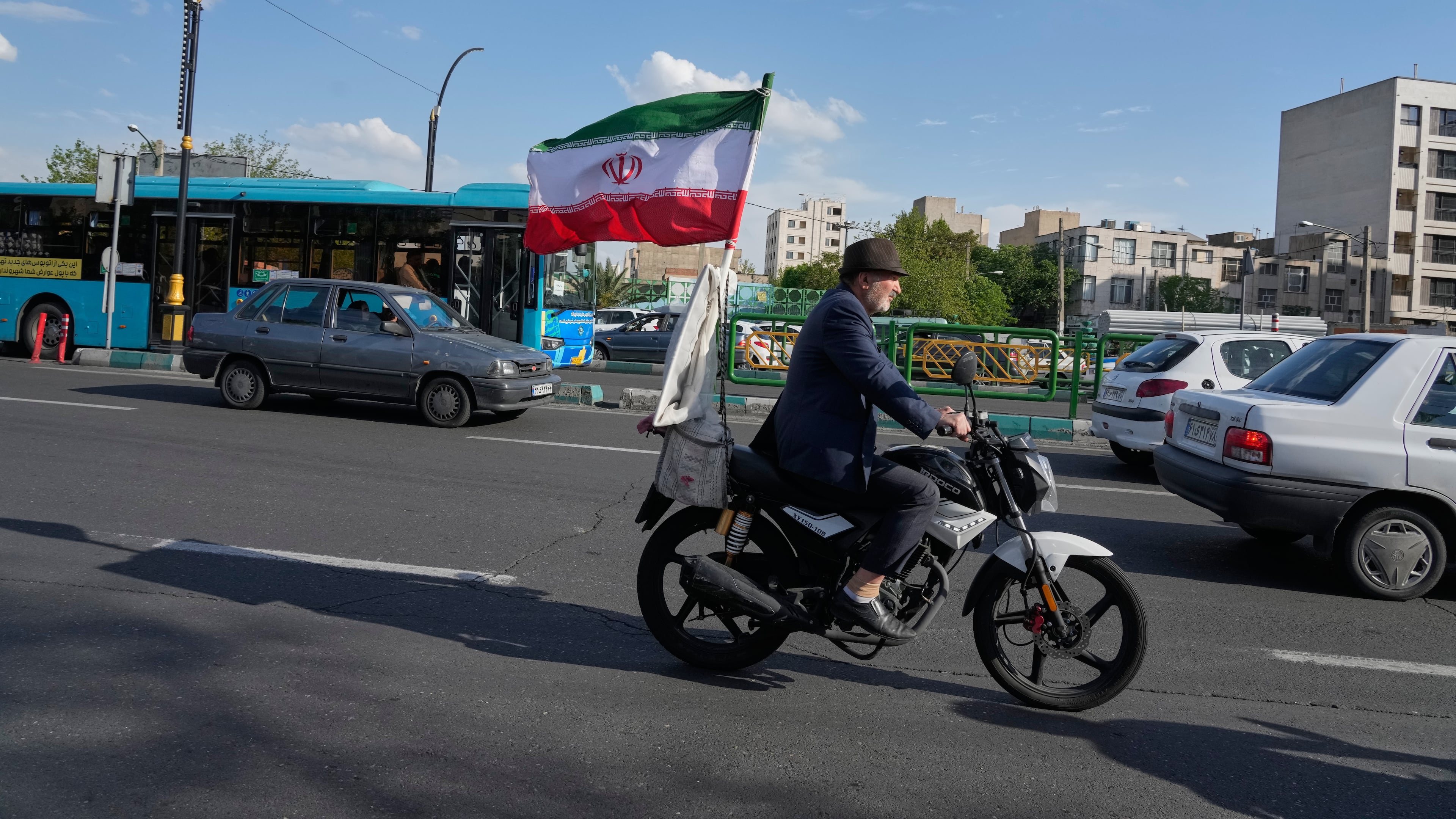 A man rides his motorbike that is adorned with an Iranian national flag, in southern Tehran, Iran, Tuesday, April 21, 2026. (AP Photo/Vahid Salemi)