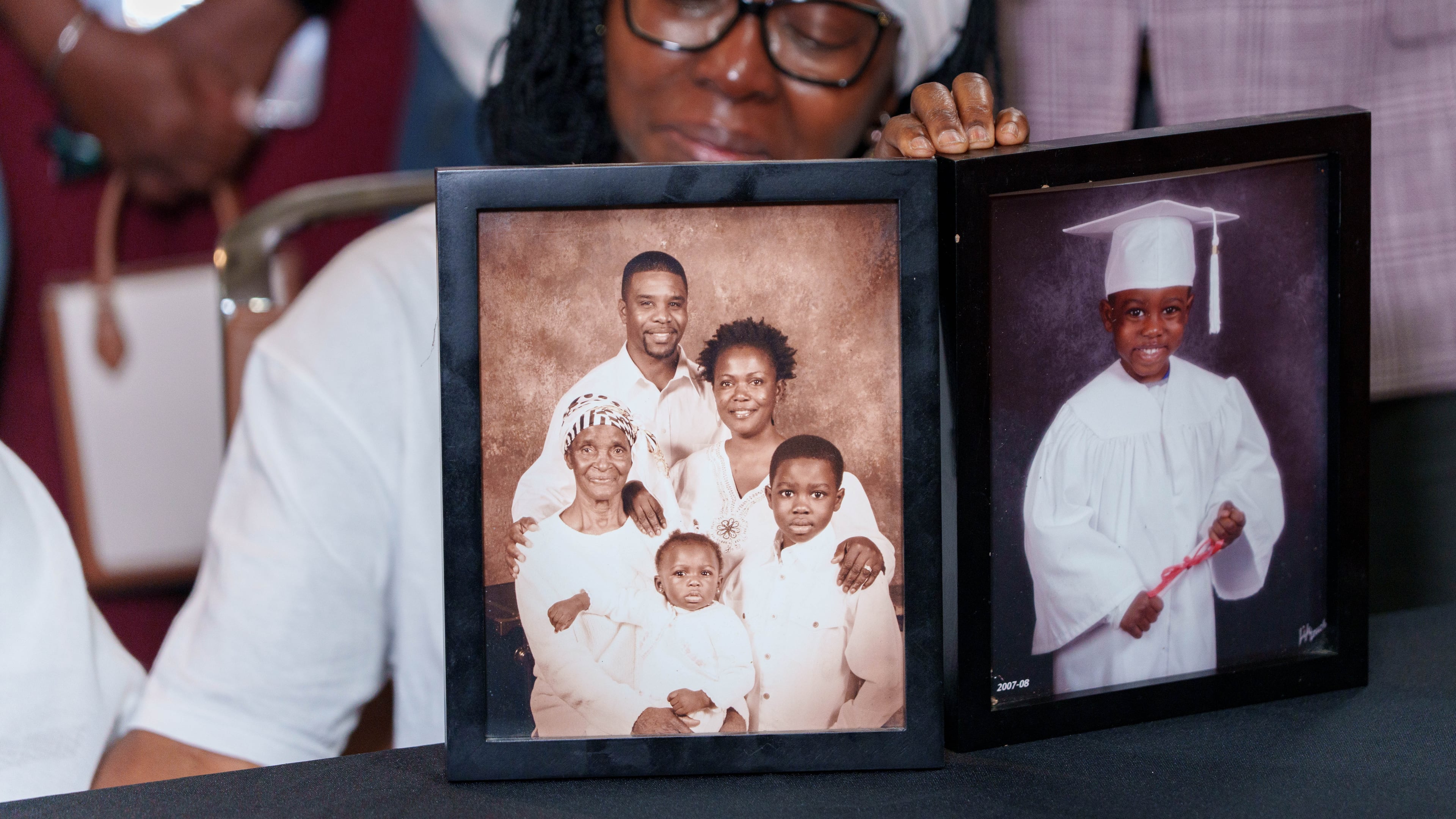 Photos of David Addo-Wright, including family portraits and pictures from his childhood, sit on a table during a news conference, Oct. 2, 2026, about his death. Addo-Wright was killed by other inmates in the DeKalb County Jail. (Ben Hendren for the AJC)