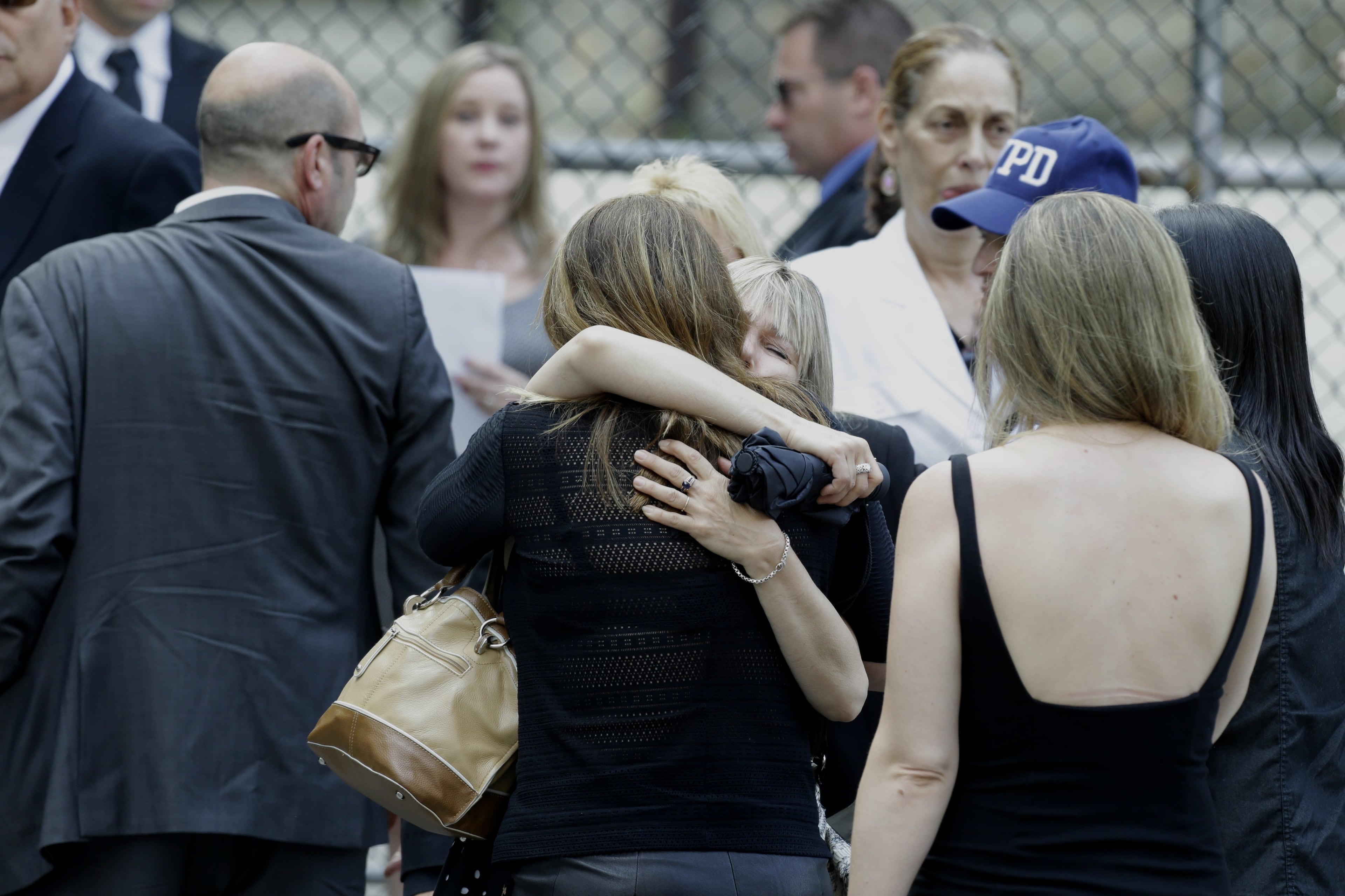 Women embrace outside of Cathedral Church of Saint John the Divine before funeral services actor James Gandolfini, Thursday, June 27, 2013, in New York. Gandolfini, who played Tony Soprano in the HBO show "The Sopranos", died while vacationing in Italy last week. (AP Photo/Julio Cortez)