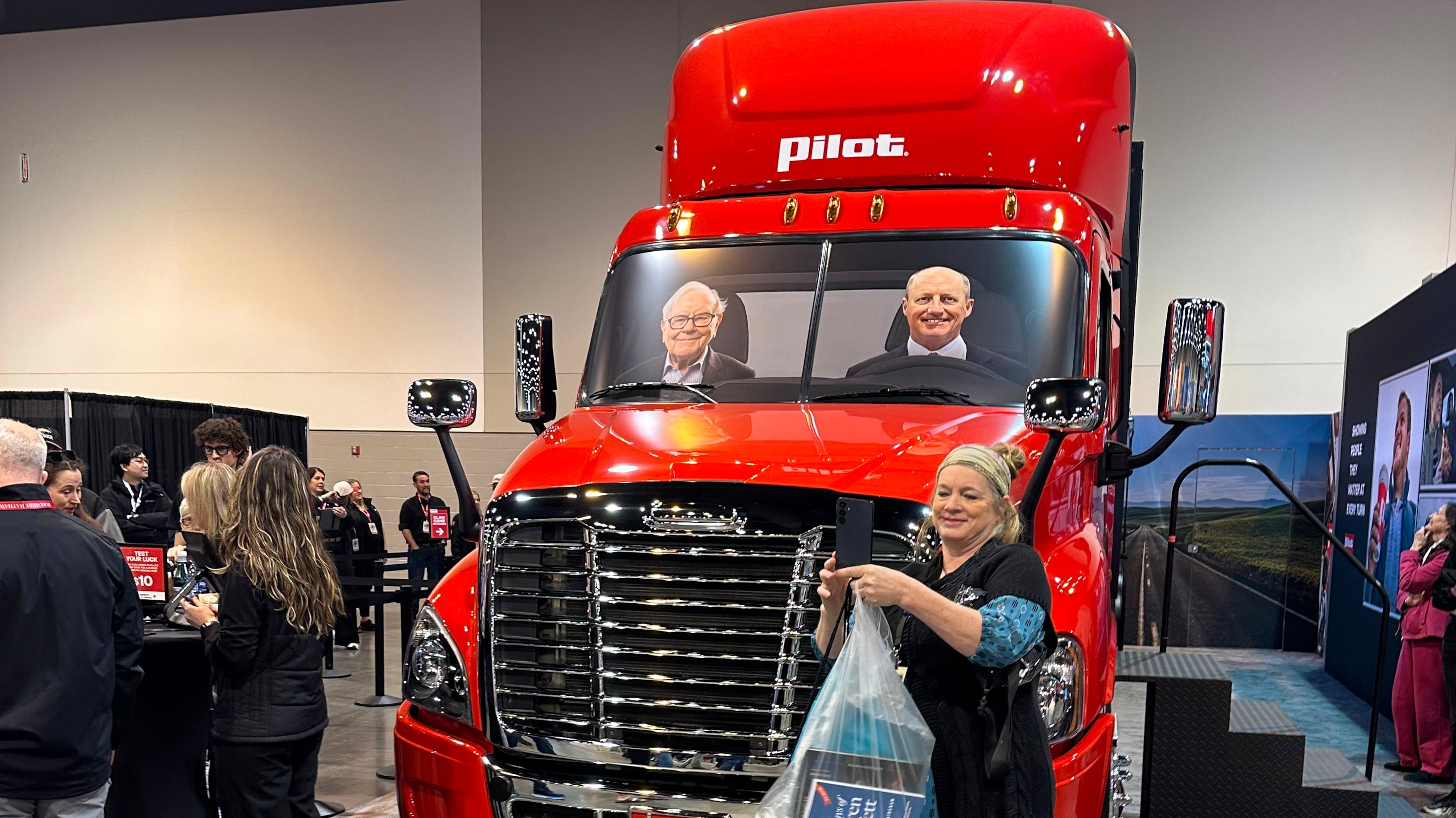 A Berkshire Hathaway shareholder takes a selfie in front of a Pilot truck stops semi truck with pictures of Berkshire's top two executives behind the wheel: new CEO Greg Abel and Chairman Warren Buffett on Friday, May 1, 2026 in Omaha, Neb. (AP Photo/Josh Funk)