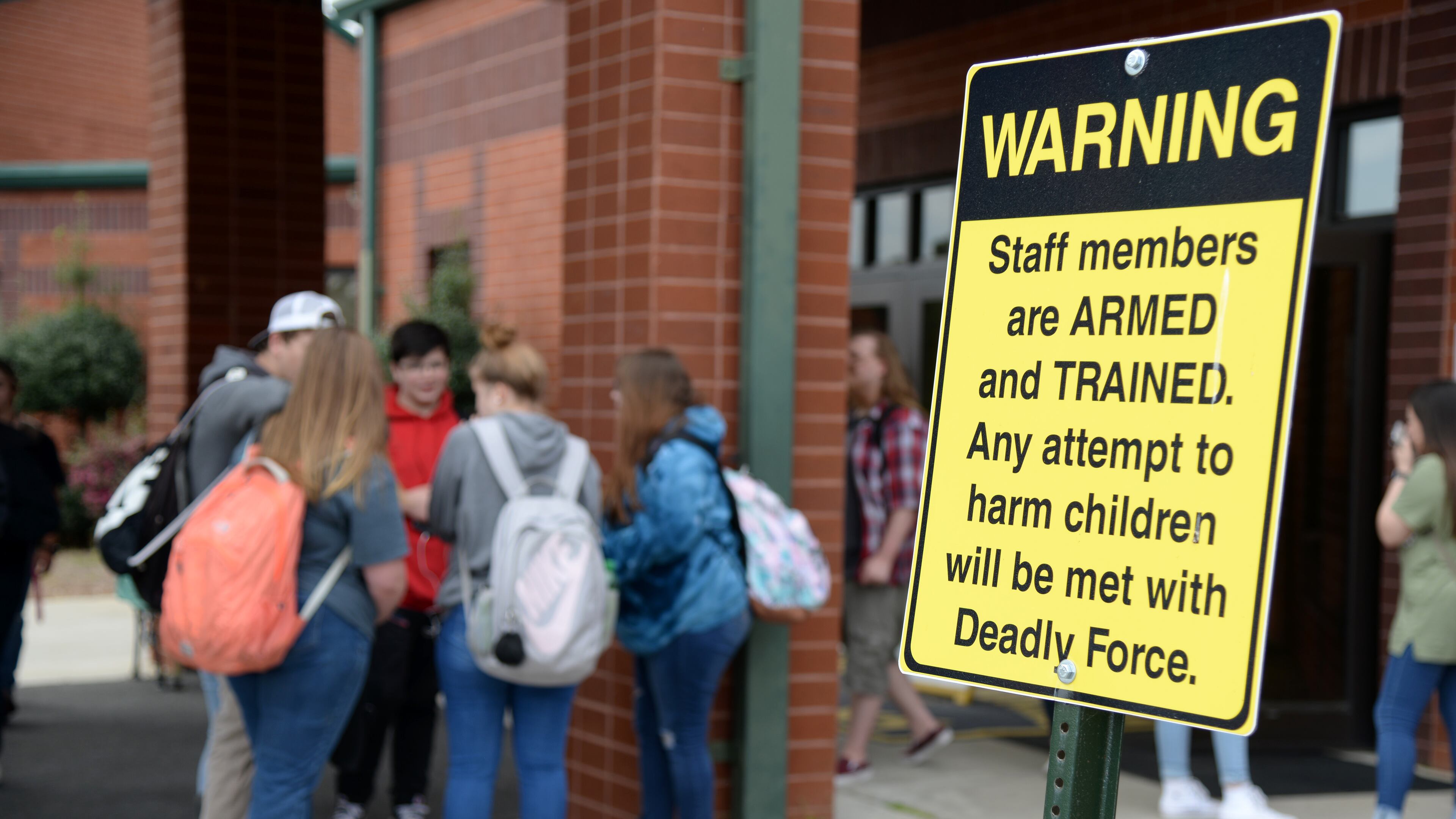 03/25/19 - Dublin - Students wait for their parents to pick them up at East Laurens Middle-High School on Monday behind a sign that warns visitors of the school that staff members are armed with weapons to protect students. Jenna Eason for The Atlanta Journal-Constitution