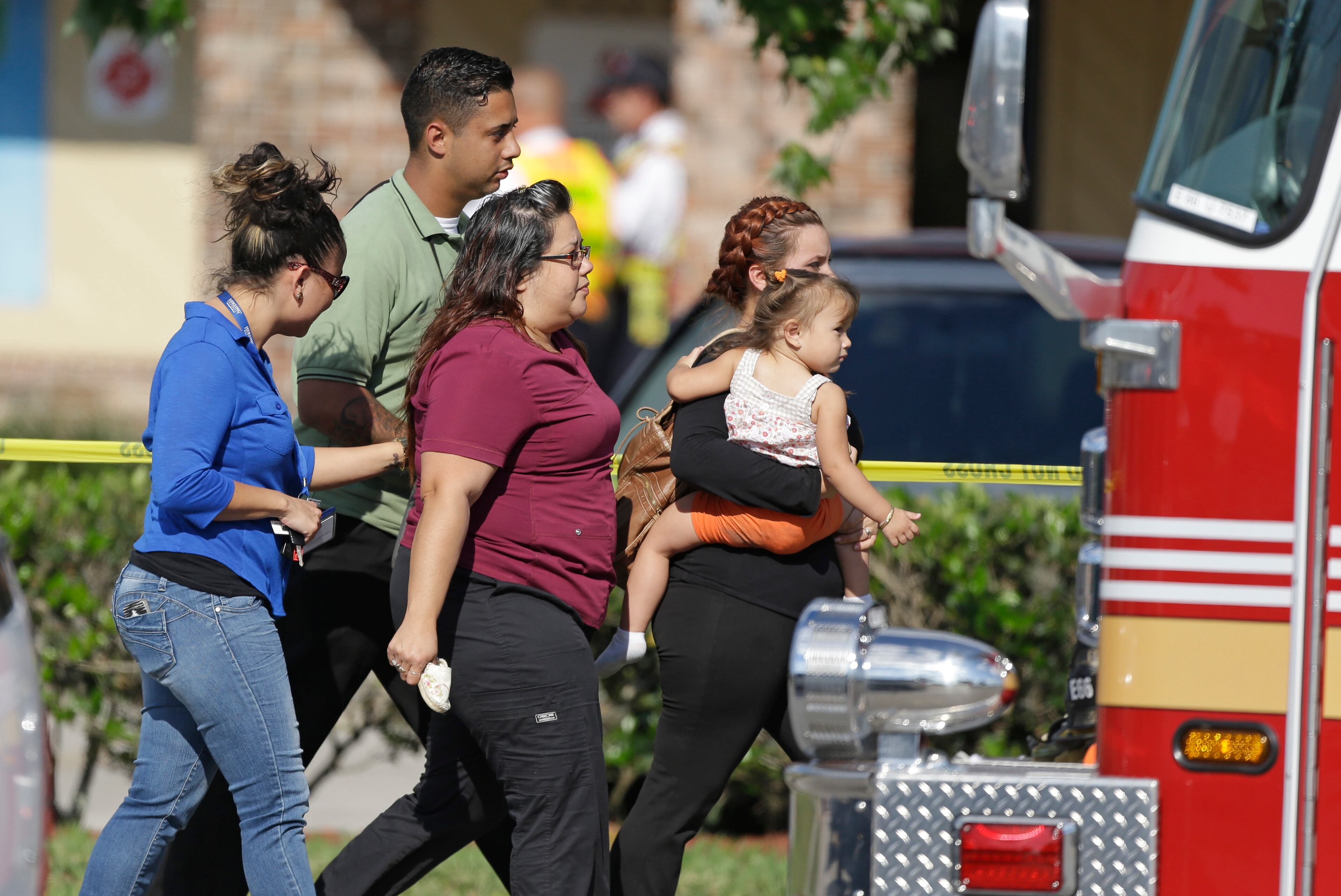 Parents and relatives leave a day care center with their children after a vehicle crashed into the center, Wednesday, April 9, 2014, in Winter Park, Fla. (AP Photo/John Raoux)