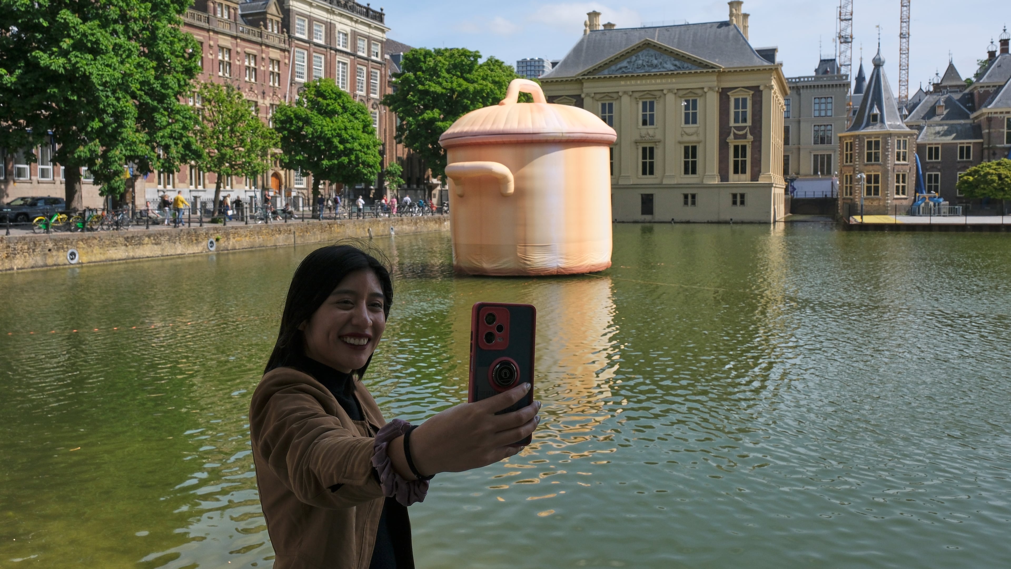 A woman takes a selfie in front of an art installation titled Like a pan in the water by Studio Job as part of the BlowUp Jubilee Art walk in the Hague, Netherlands, Thursday, May 21, 2026. (AP Photo/Patrick Post)