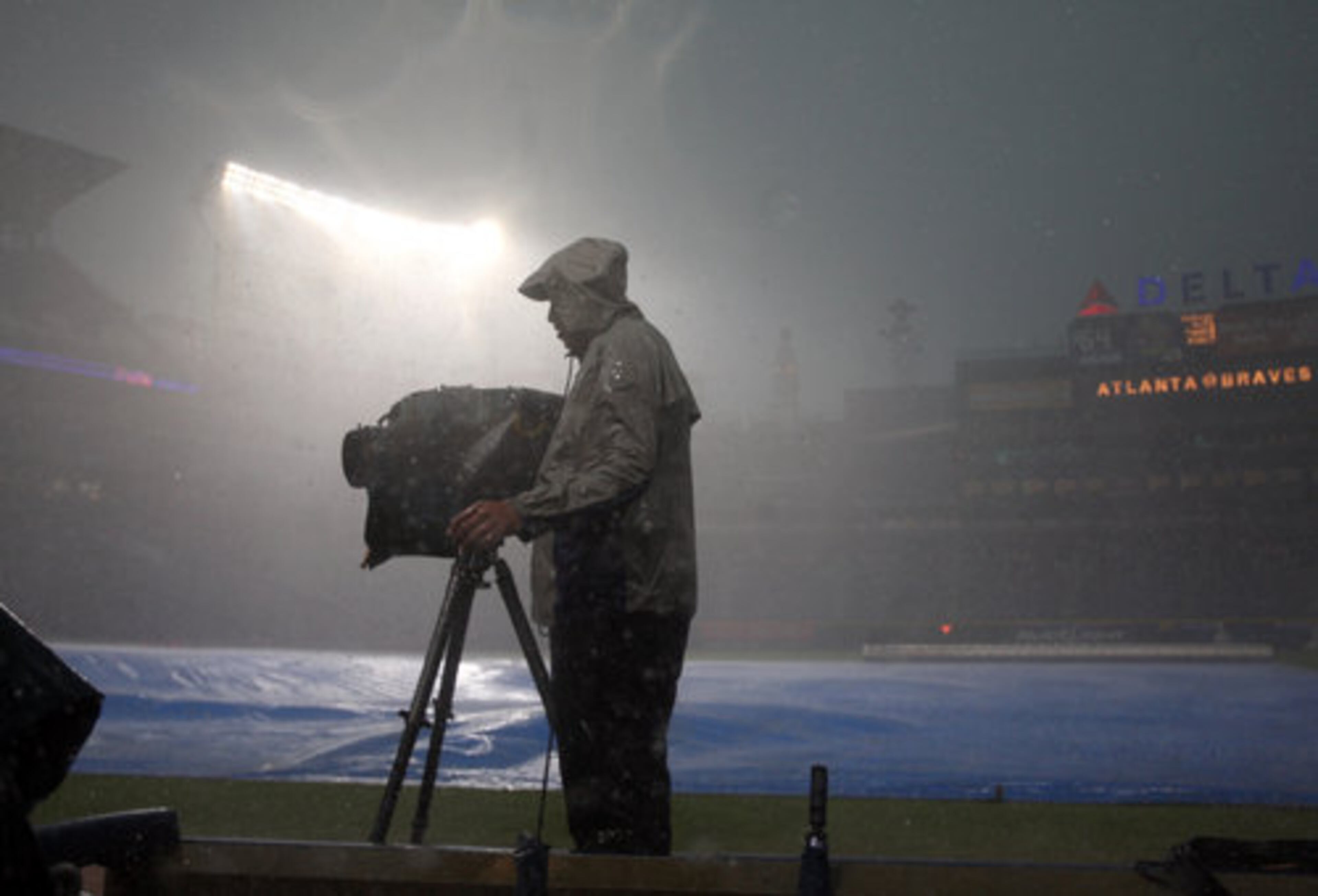 Jason Upson, a cameraman with Fox Sport South, stands in the pouring rain as he videotapes the pre-game show. The game between the Braves and Astros was delayed by the weather.