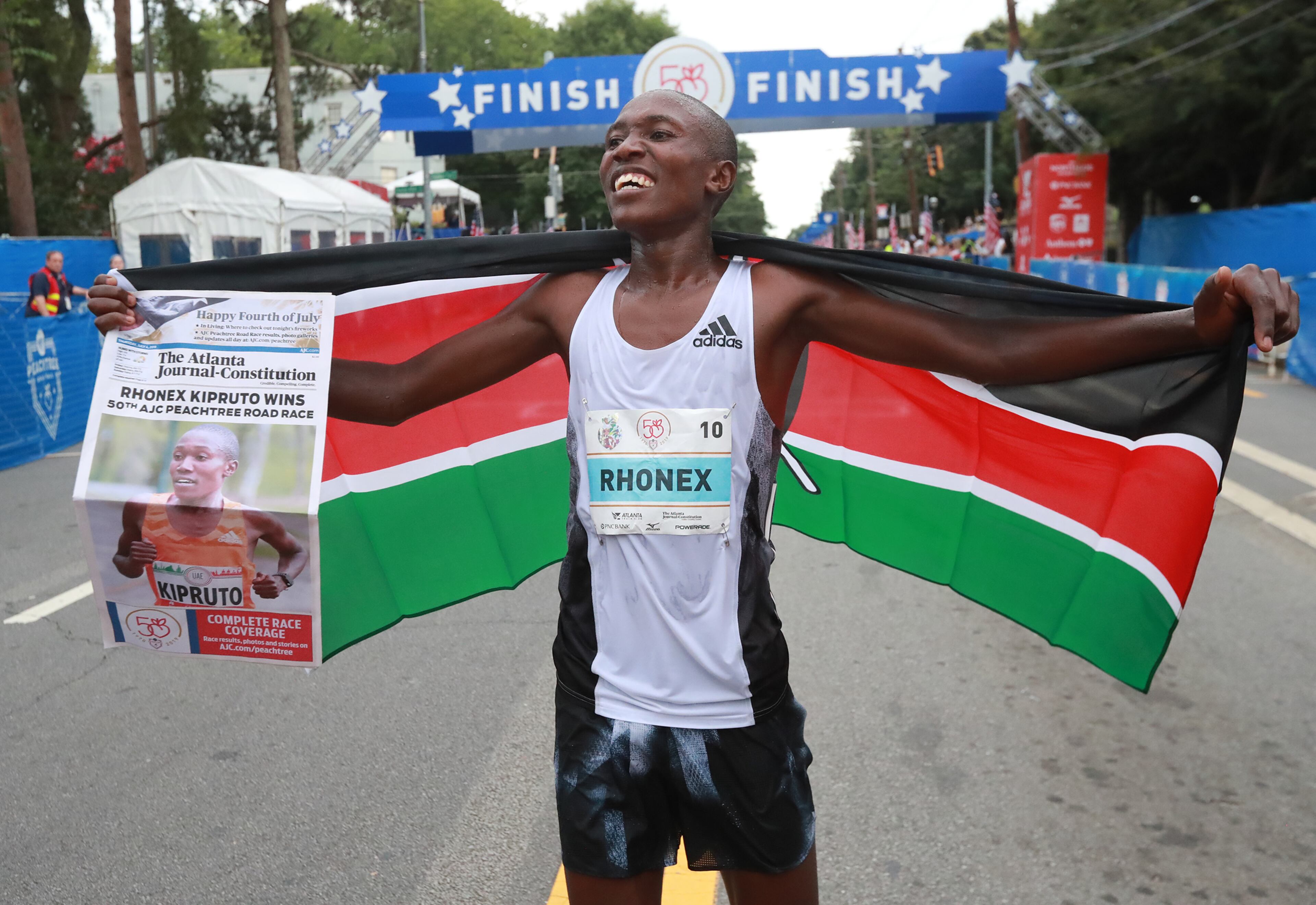 Rhonex Kipruto celebrates winning the 50th AJC Peachtree Road Race in record time on Thursday. Curtis Compton/ccompton@ajc.com