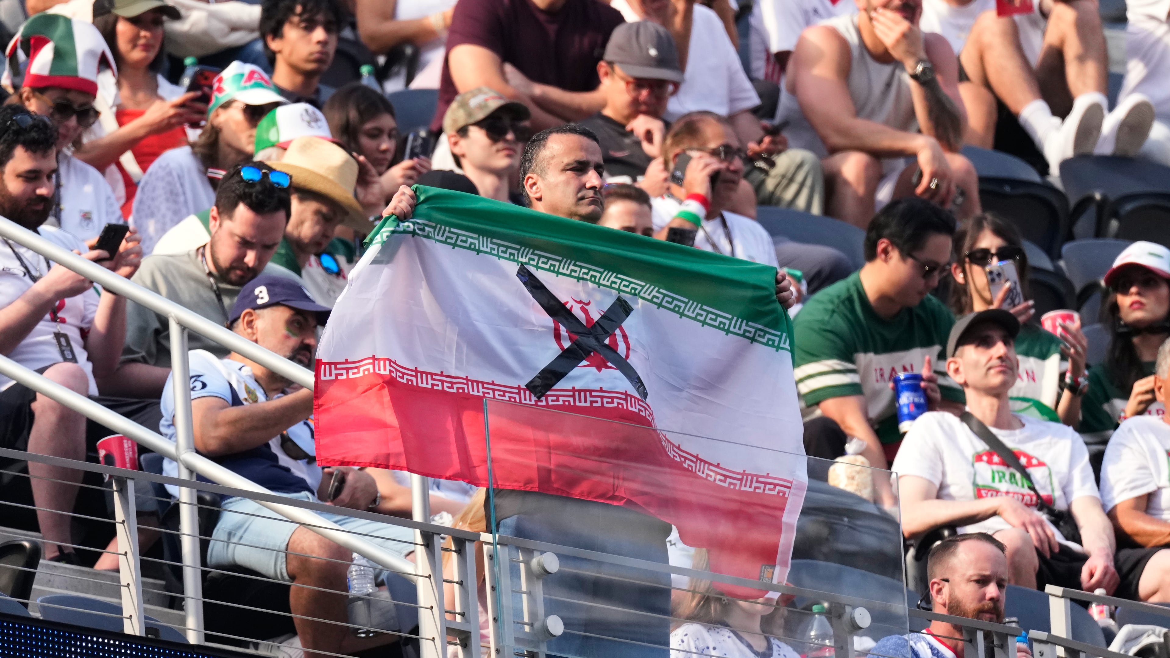 An attendees holds an Iranian flag with an "X" on it before the World Cup Group G soccer match between Iran and New Zealand in Inglewood, Calif., near Los Angeles, Monday, June 15, 2026. (AP Photo/Mark J. Terrill)