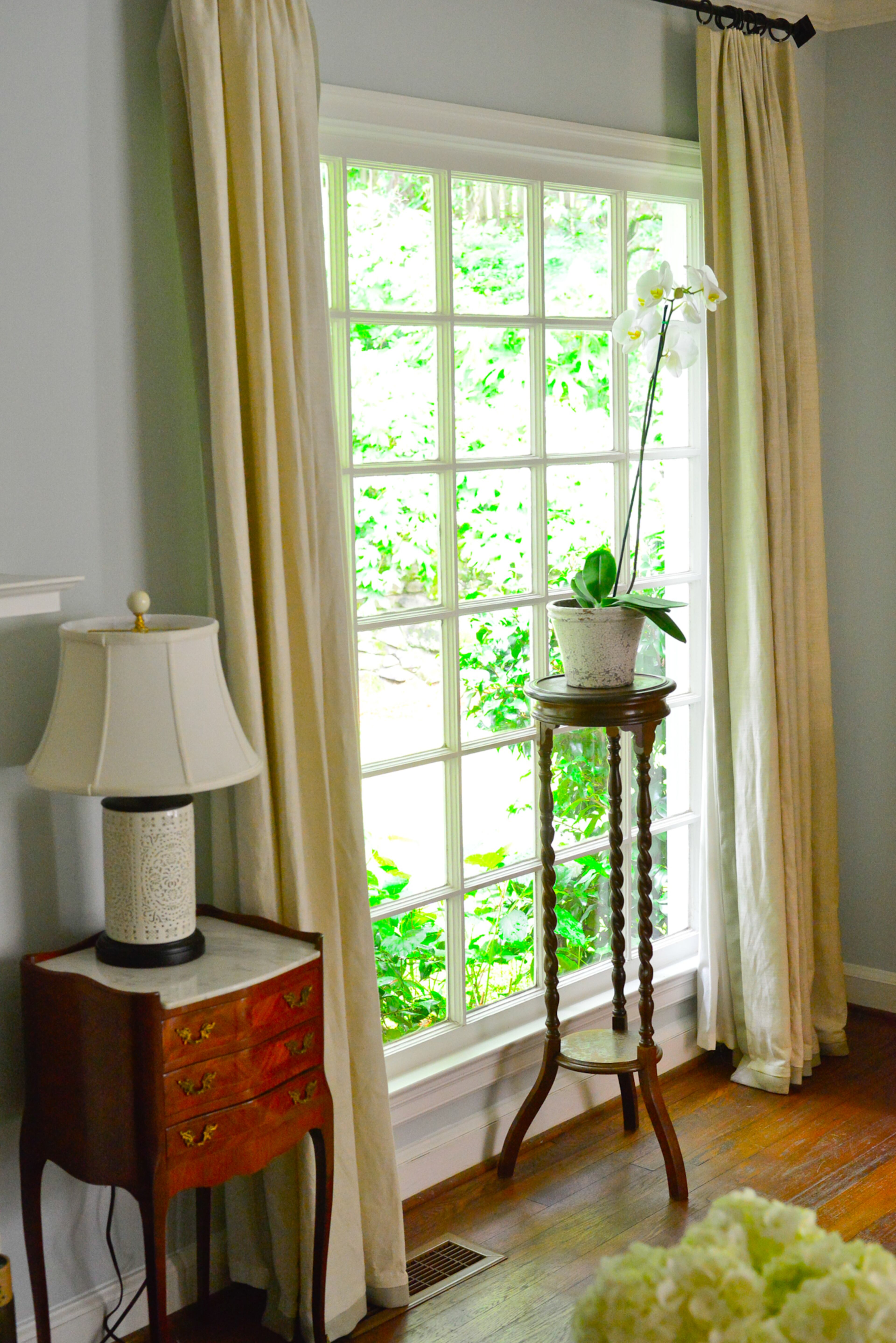 Antiques include French marble-topped end tables inherited from homeowner Catherine Callaway's grandparents. Custom-made draperies flank a big picture window offering views of the backyard.
