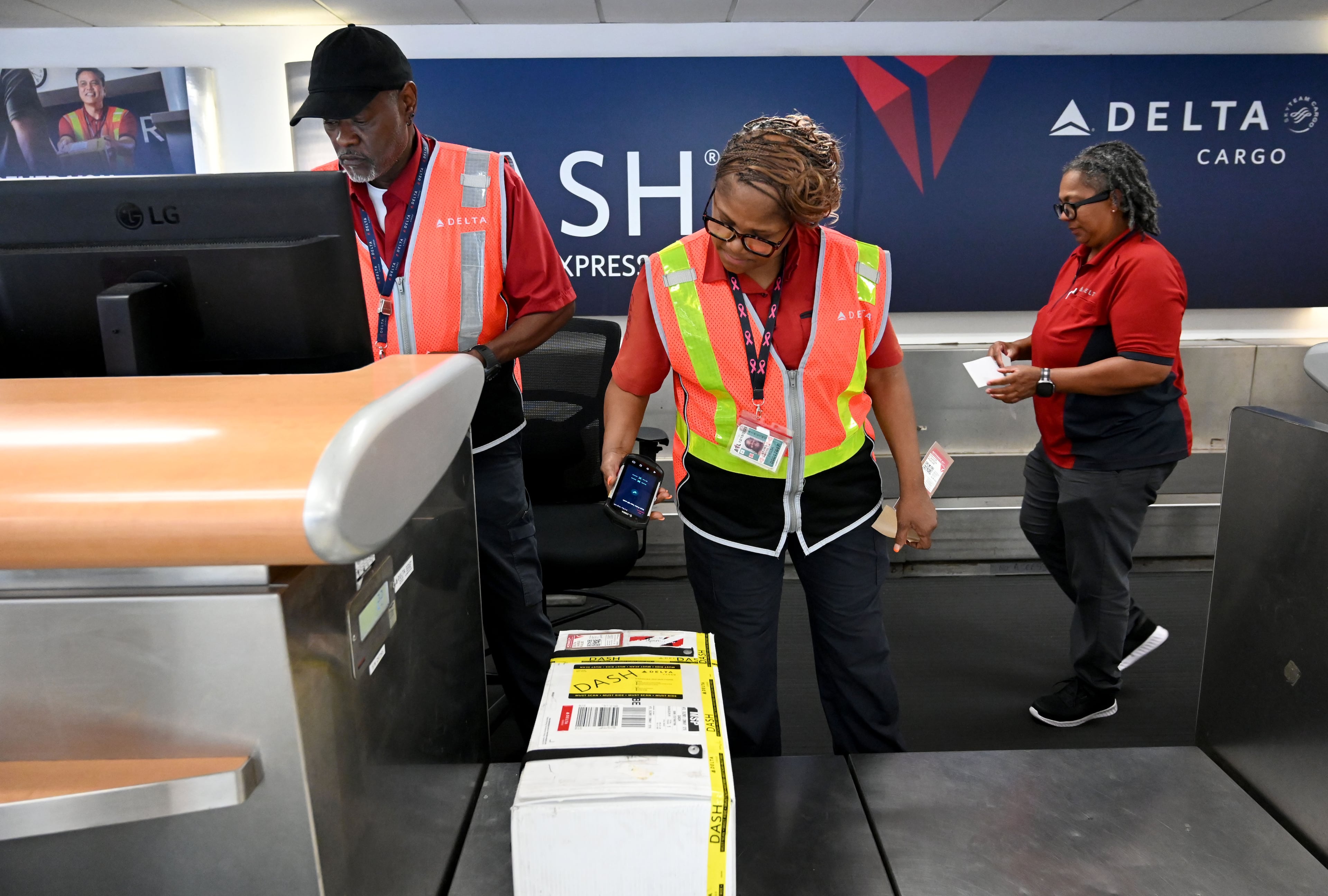 (From left) Kirkland Gibbs, Priscilla Lyons and Doris Minus handle package drop-off for Delta DASH shipping services at Hartsfield-Jackson Atlanta International Airport on Thursday, May 28, 2026. (Hyosub Shin/AJC)