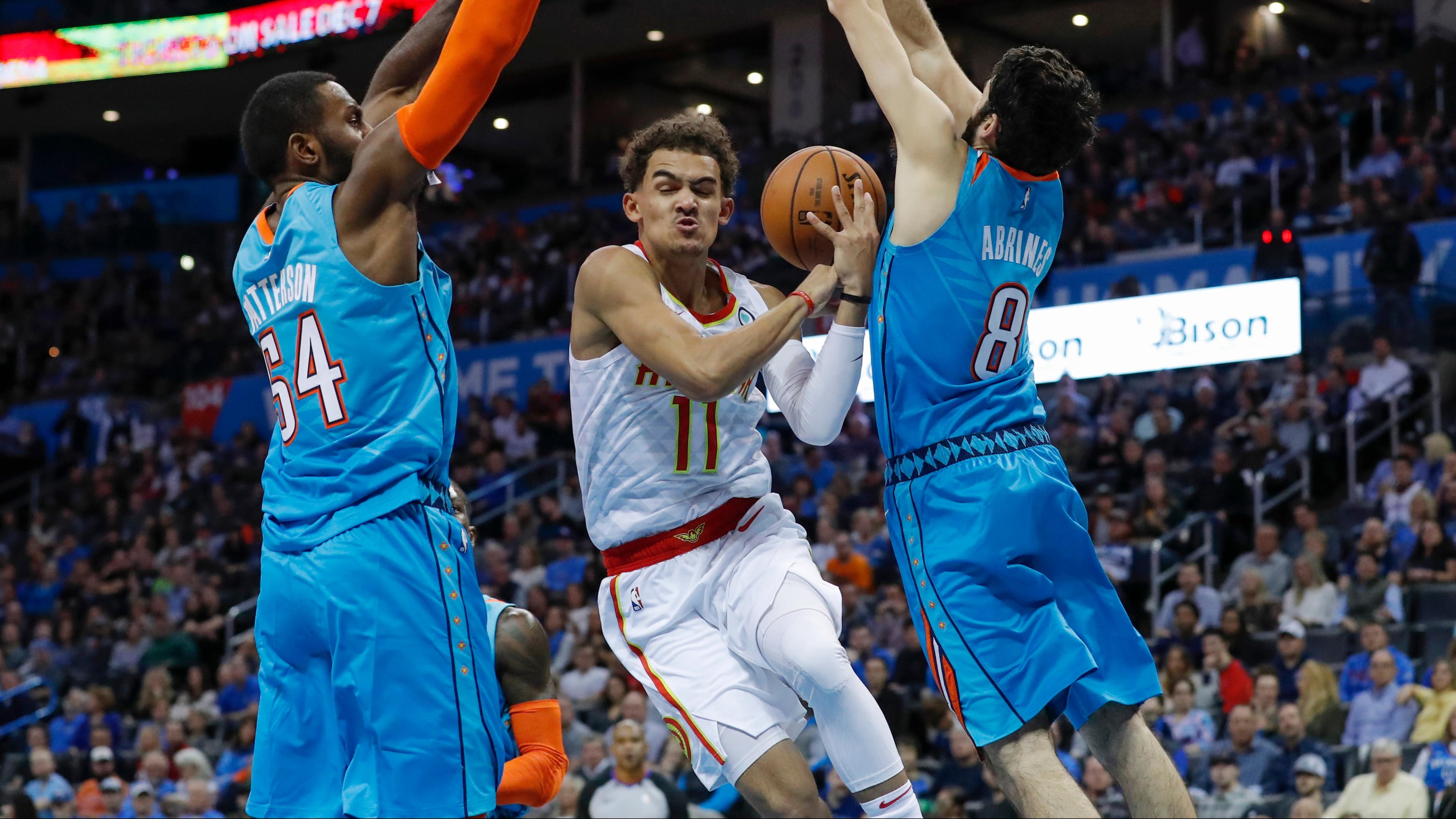 Hawks guard Trae Young (11) goes to the basket between Oklahoma City Thunder forward Patrick Patterson (54) and guard Alex Abrines (8) during the first half of an NBA basketball game in Oklahoma City, Friday, Nov. 30, 2018. (AP Photo/Alonzo Adams)