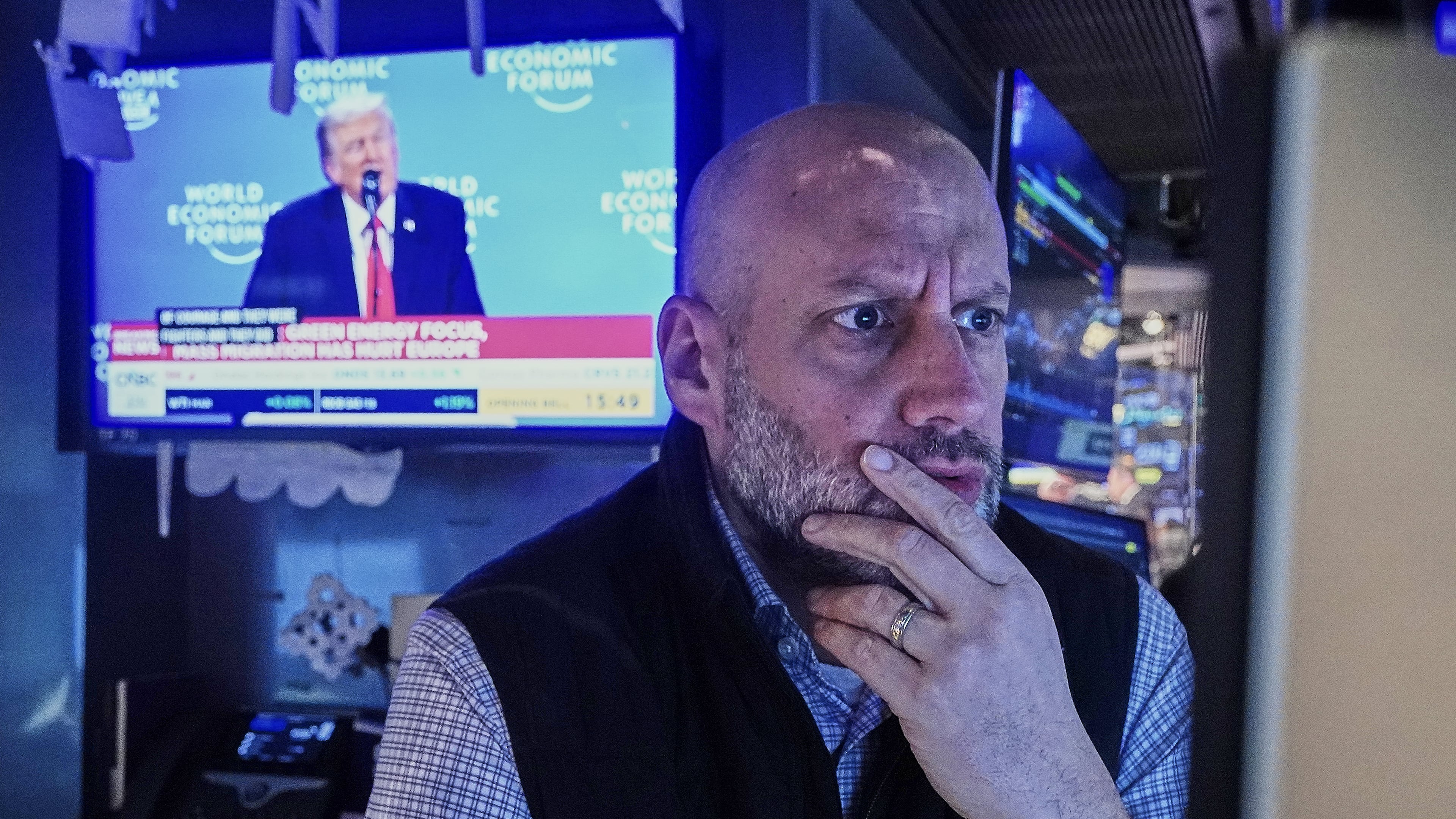 Specialist Meric Greenbaum works at his post on the floor of the New York Stock Exchange, as a television shows President Donald Trump speaking at the World Economic Forum, Wednesday, Jan. 21, 2026. (AP Photo/Richard Drew)