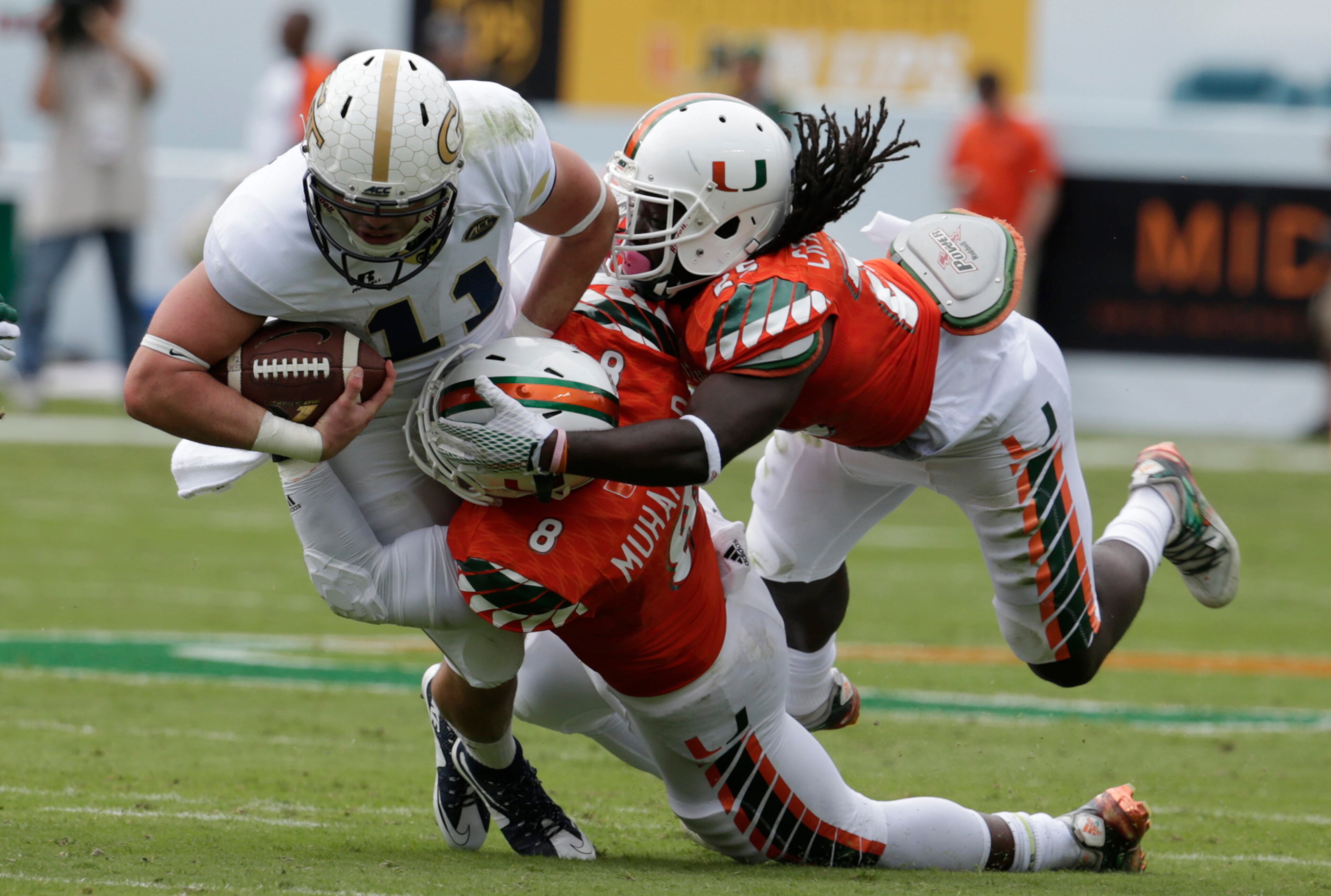 Georgia Tech quarterback Matthew Jordan (11) is brought down by Miami defensive lineman Al-Quadin Muhammad (8) and defensive back Dallas Crawford, right, during the first half of an NCAA college football game, Saturday, Nov. 21, 2015 in Miami Gardens, Fla. (AP Photo/Lynne Sladky)