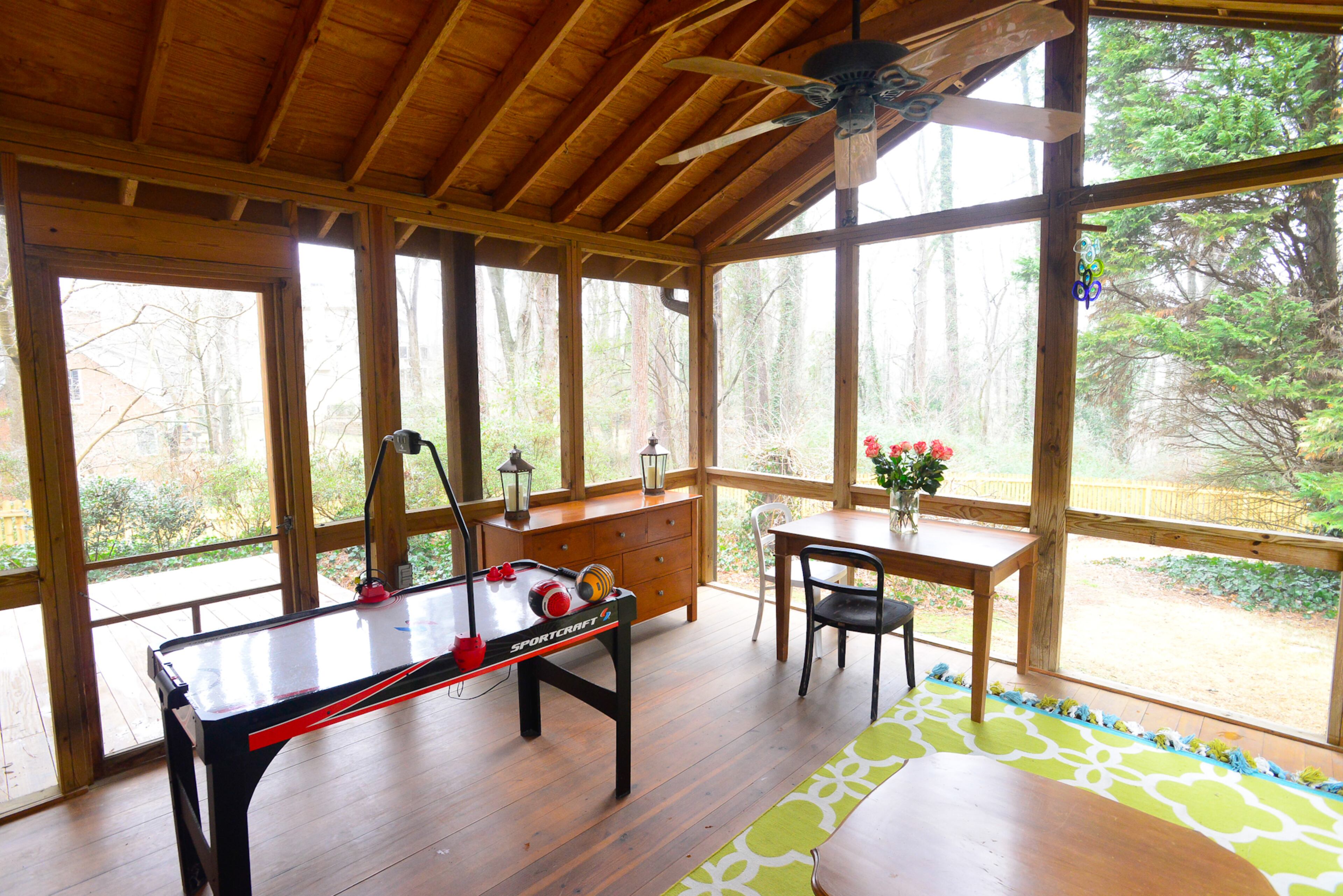 A screened back porch has a rustic touch and provides ample room to read and play games such as air hockey. The rug is from World Market.