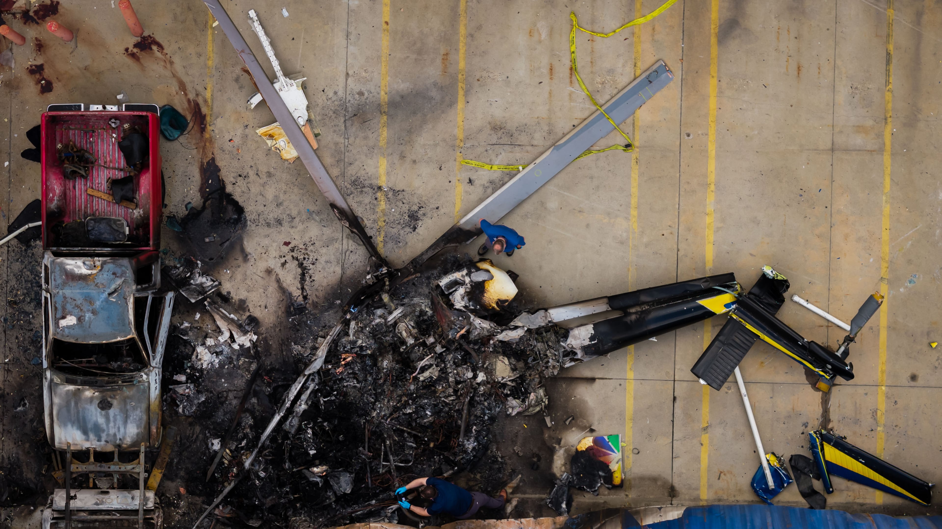 In this aerial view, people investigate the aftermath of a news helicopter crash in Chatsworth, a neighborhood in Los Angeles, on Wednesday, Sept. 16, 2026.(AP Photo/Ethan Swope)