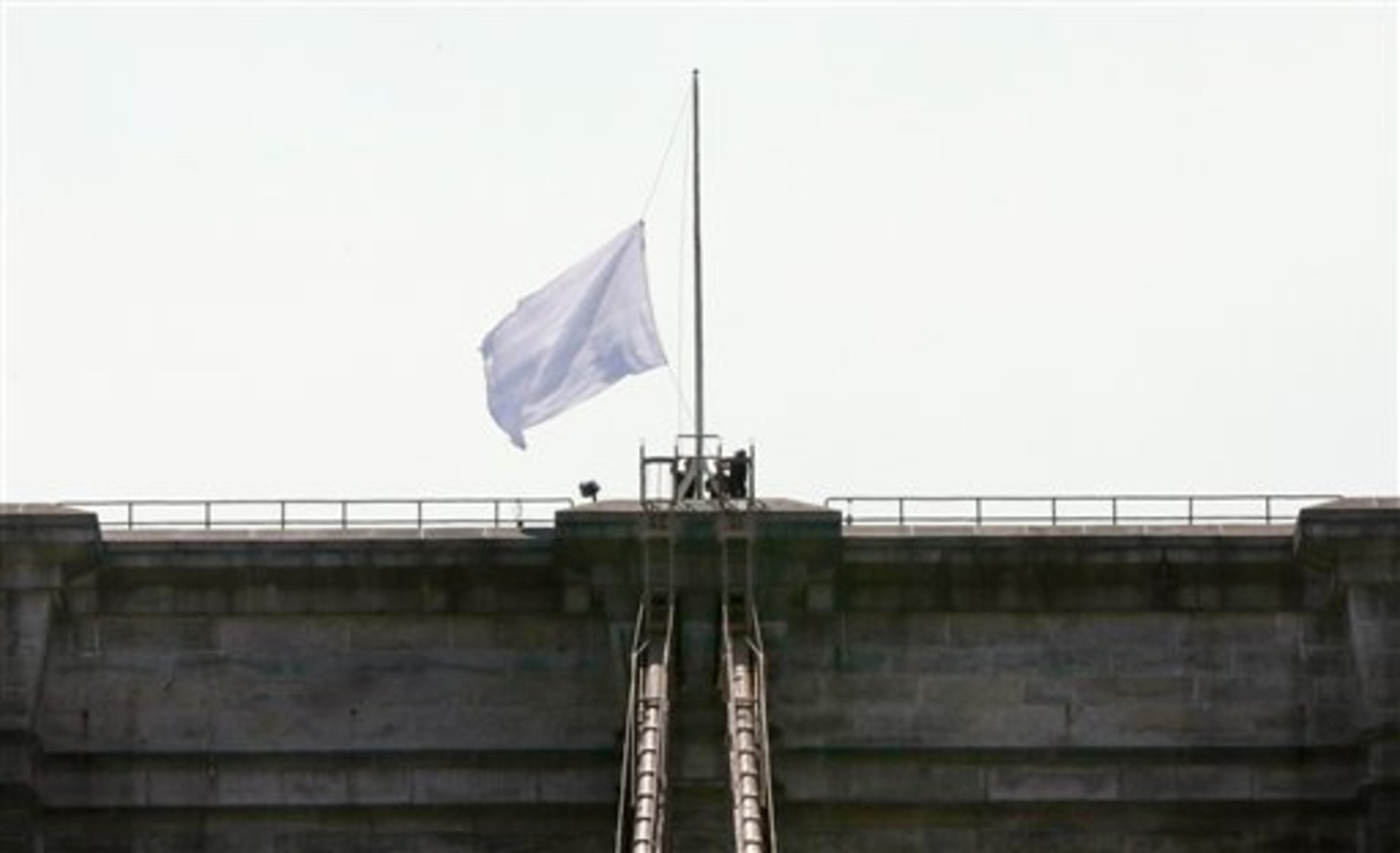 New York City Police officers lower a white flag flying atop the west tower of New York's Brooklyn Bridge, Tuesday, July 22, 2014. Someone replaced two American flags on the bridge with mysterious white flags. The white flags, international symbols of surrender, fluttered from poles on the stone supports that hold cables above the bridge connecting Brooklyn and Manhattan. An entity called Bike Lobby tweeted Tuesday that it hoisted the flags to signal �surrender of the Brooklyn Bridge bicycle path to pedestrians.� (AP Photo/Richard Drew)